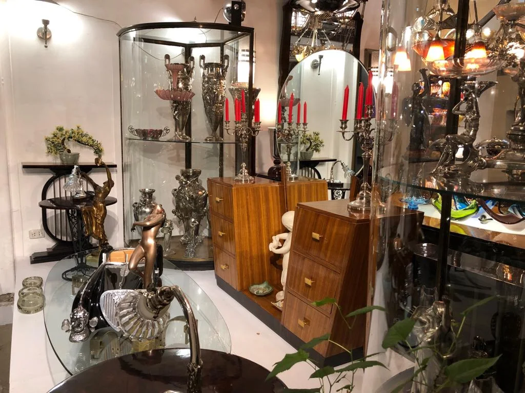 Showcase with antiques various decorative items and red candlesticks in Luxury Design Store