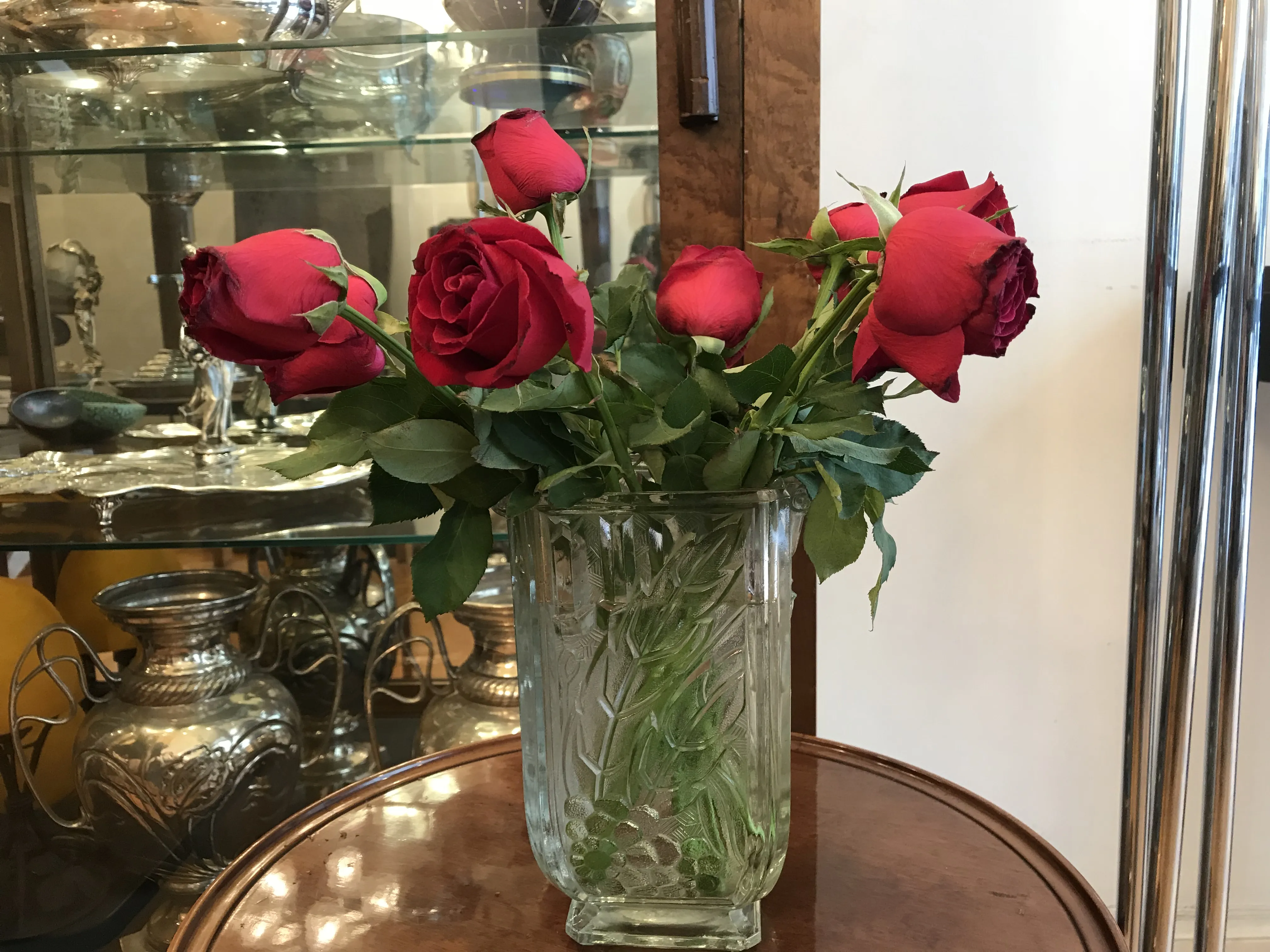 Arranjo de várias rosas antigas em um vaso transparente.