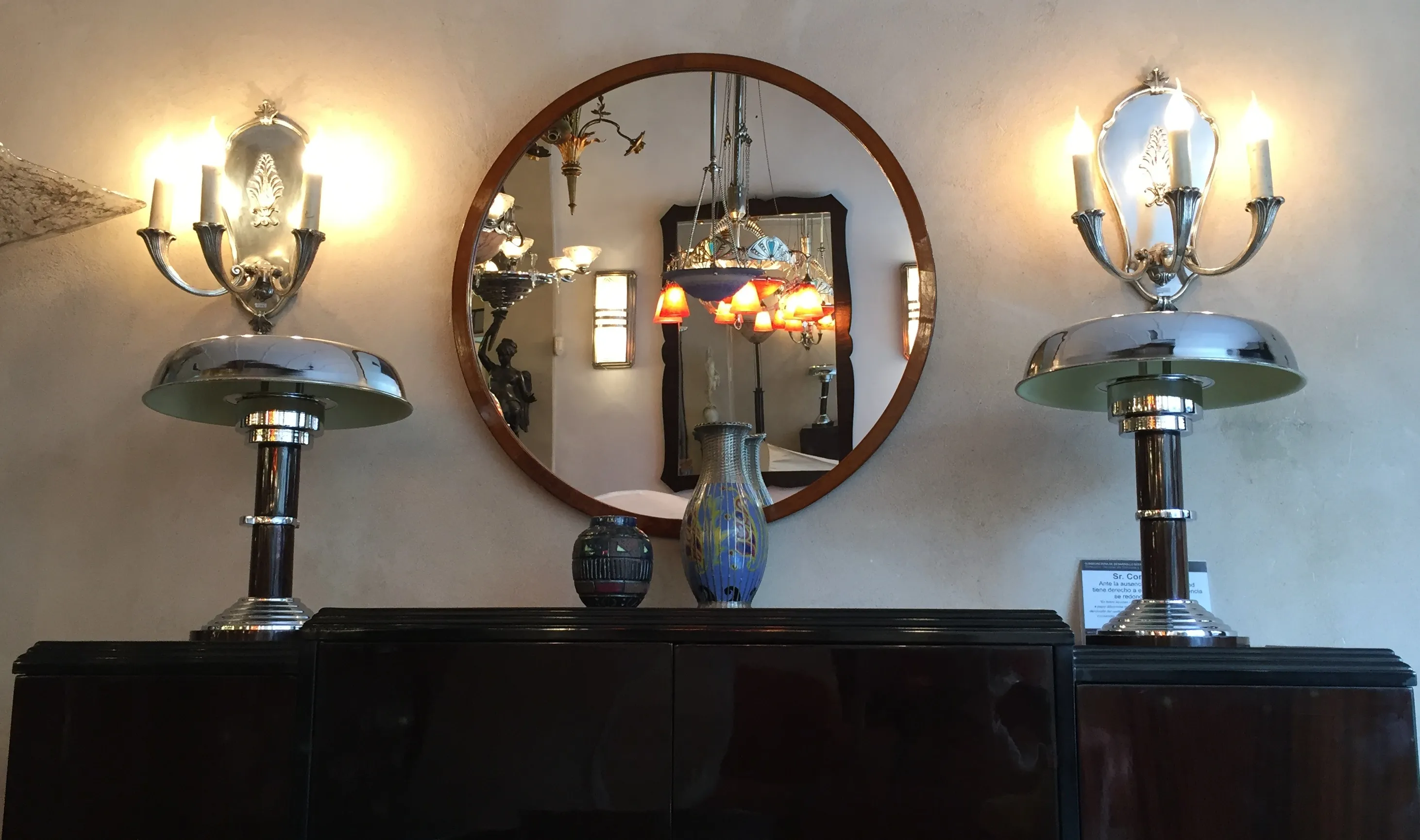 rundes antikes Spiegel an der Wand mit Lampen und dekorativen Vasen