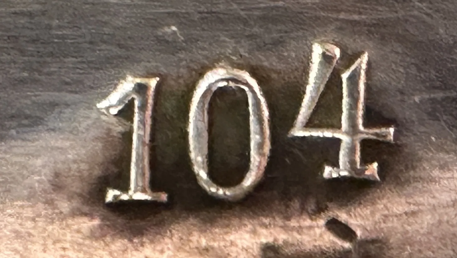Detail of an antique with serial number 104 visible.
