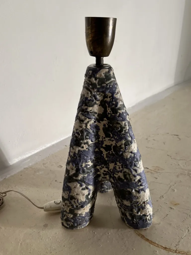 Lampada da tavolo antica con design astratto e base a forma di A su una superficie chiara.