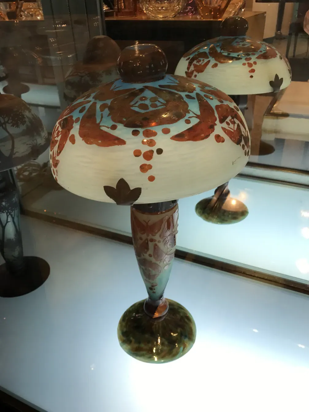 古董玻璃件带有装饰细节和签名，展现明亮的色彩，陈列在优雅的环境中。