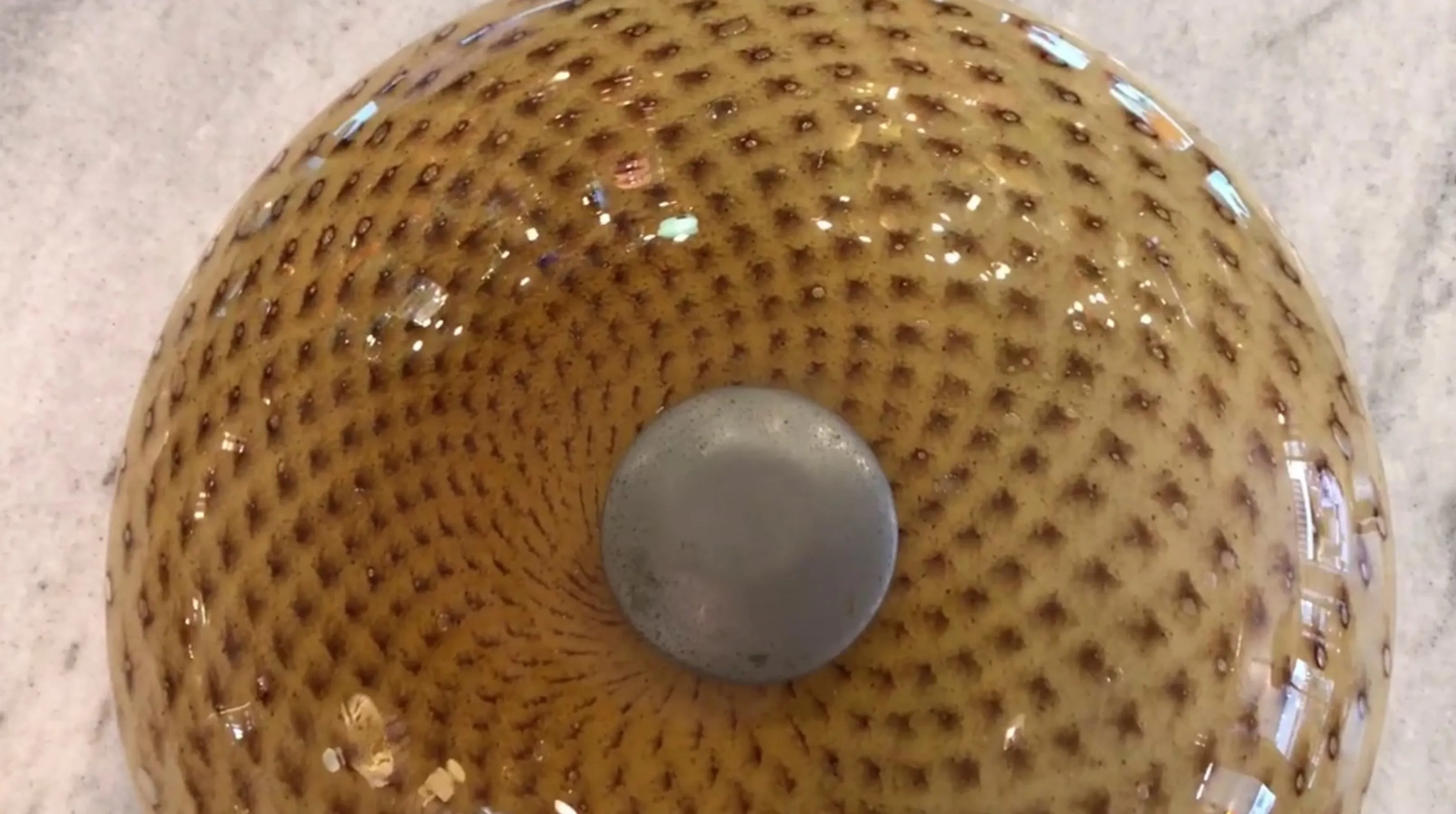 पुरानी छत की रोशनी जिसमें जाल जैसी पैटर्न और धातु केंद्र है