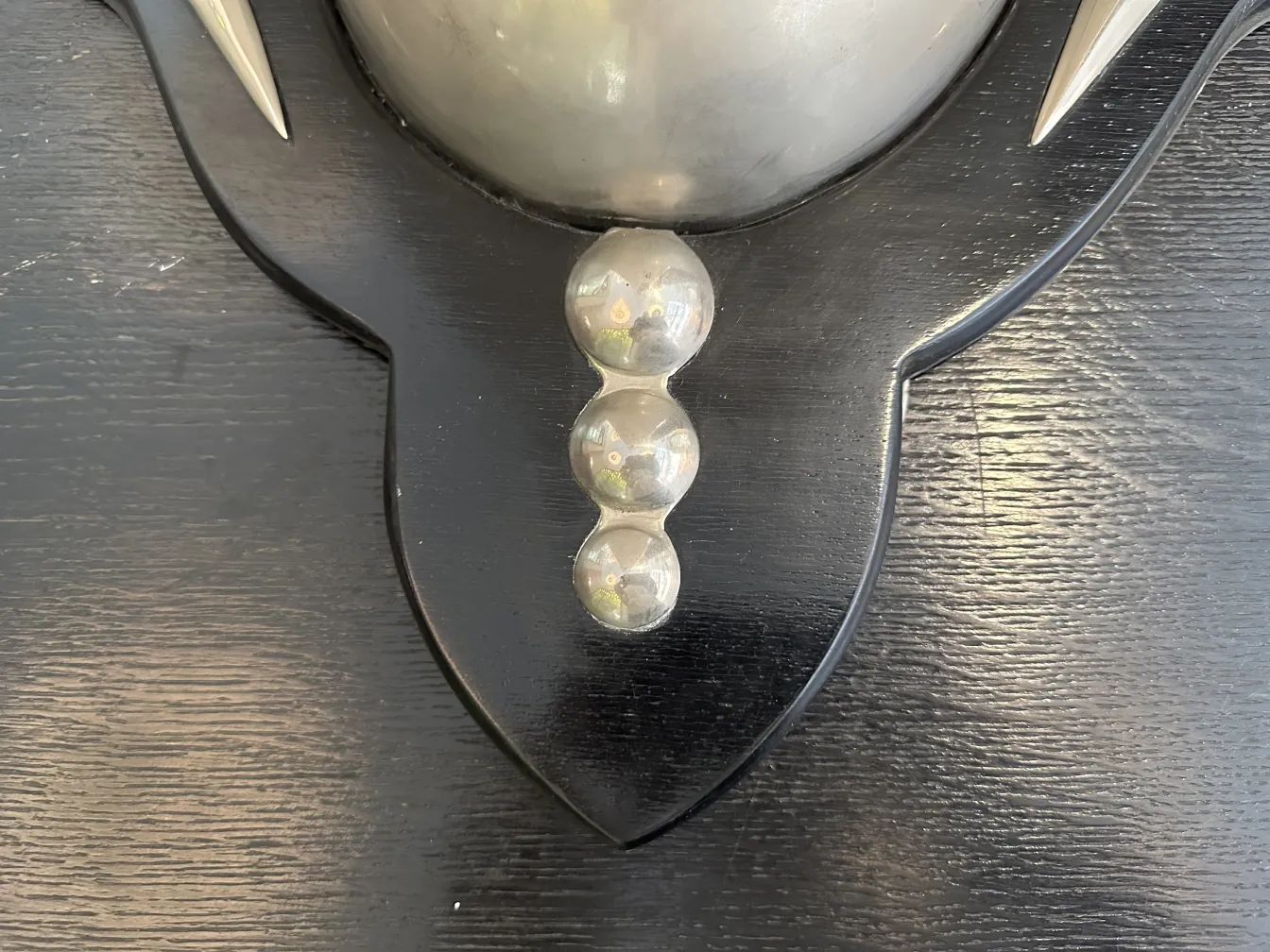 प्राचीन स्कोनस की जोड़ी, जिसमें गोलाकार विवरण हैं, अंधेरी दीवार पर सजाई गई है