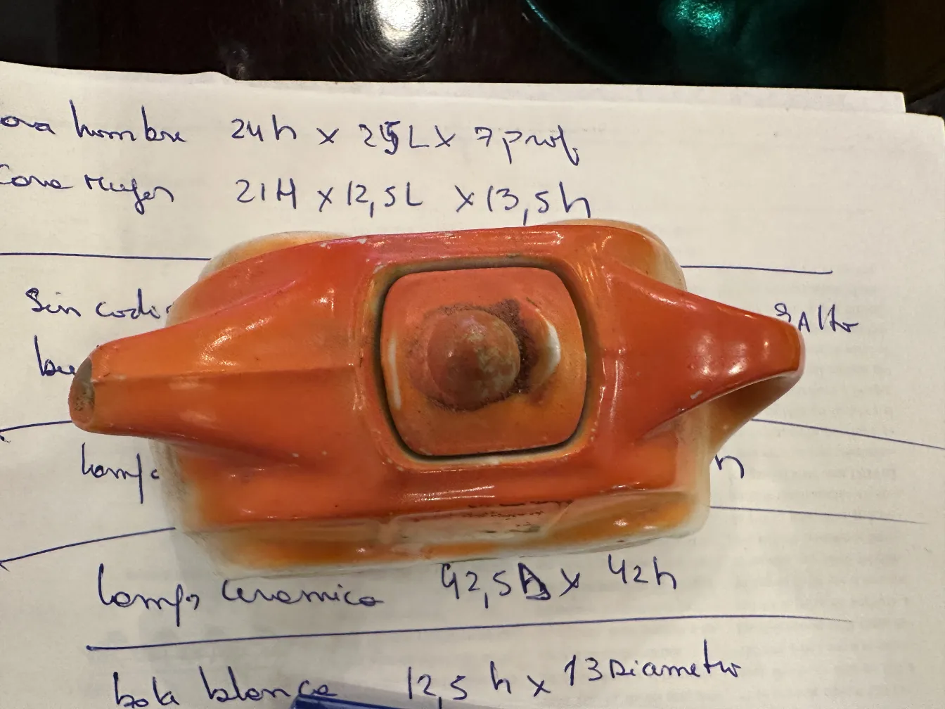 オレンジと白の古い陶器オブジェ、書かれた紙の背景に特徴的なディテール。