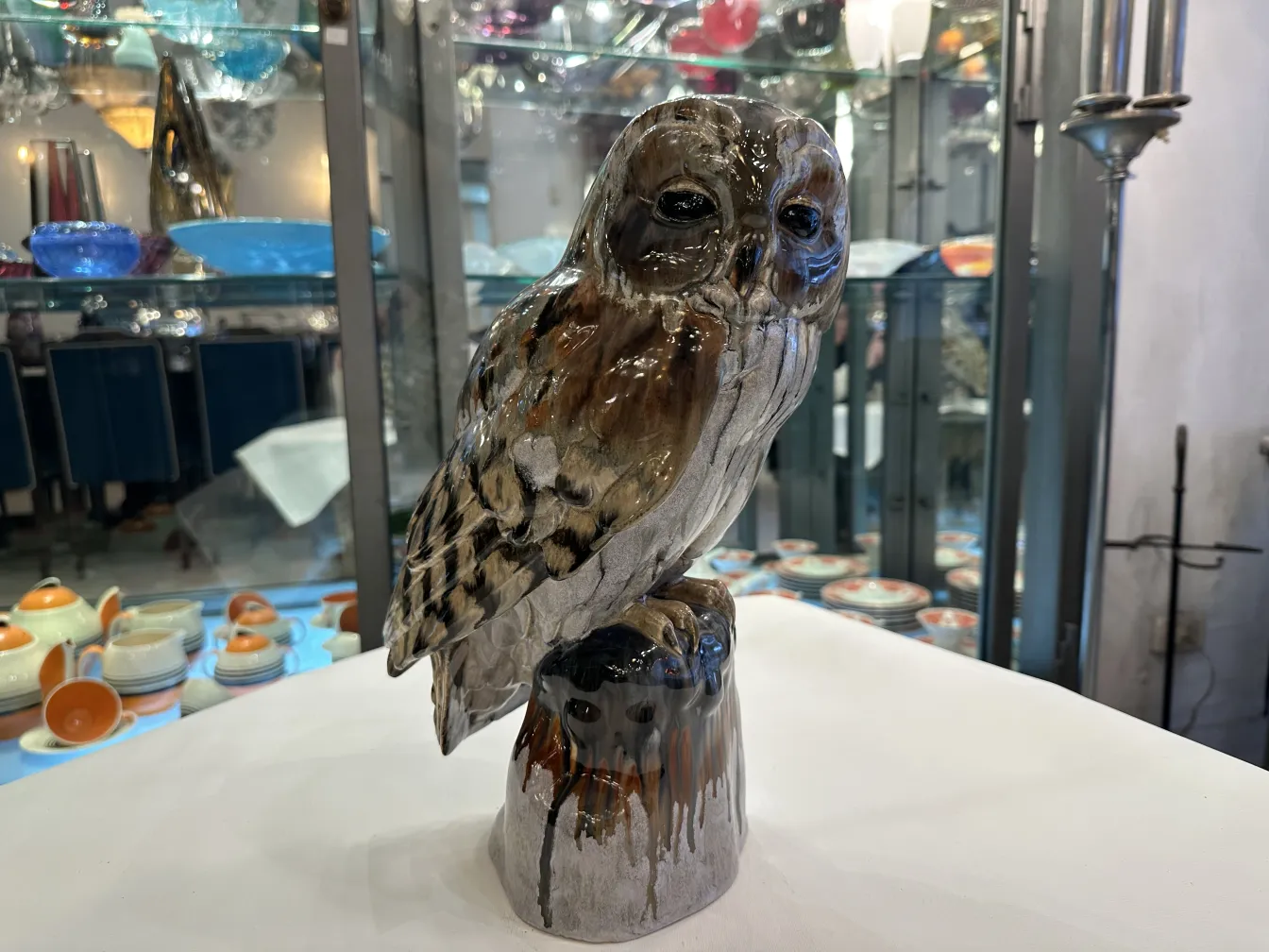 Figura antica in ceramica a forma di gufo, colore realistico, esposta in un ambiente di antiquariato.