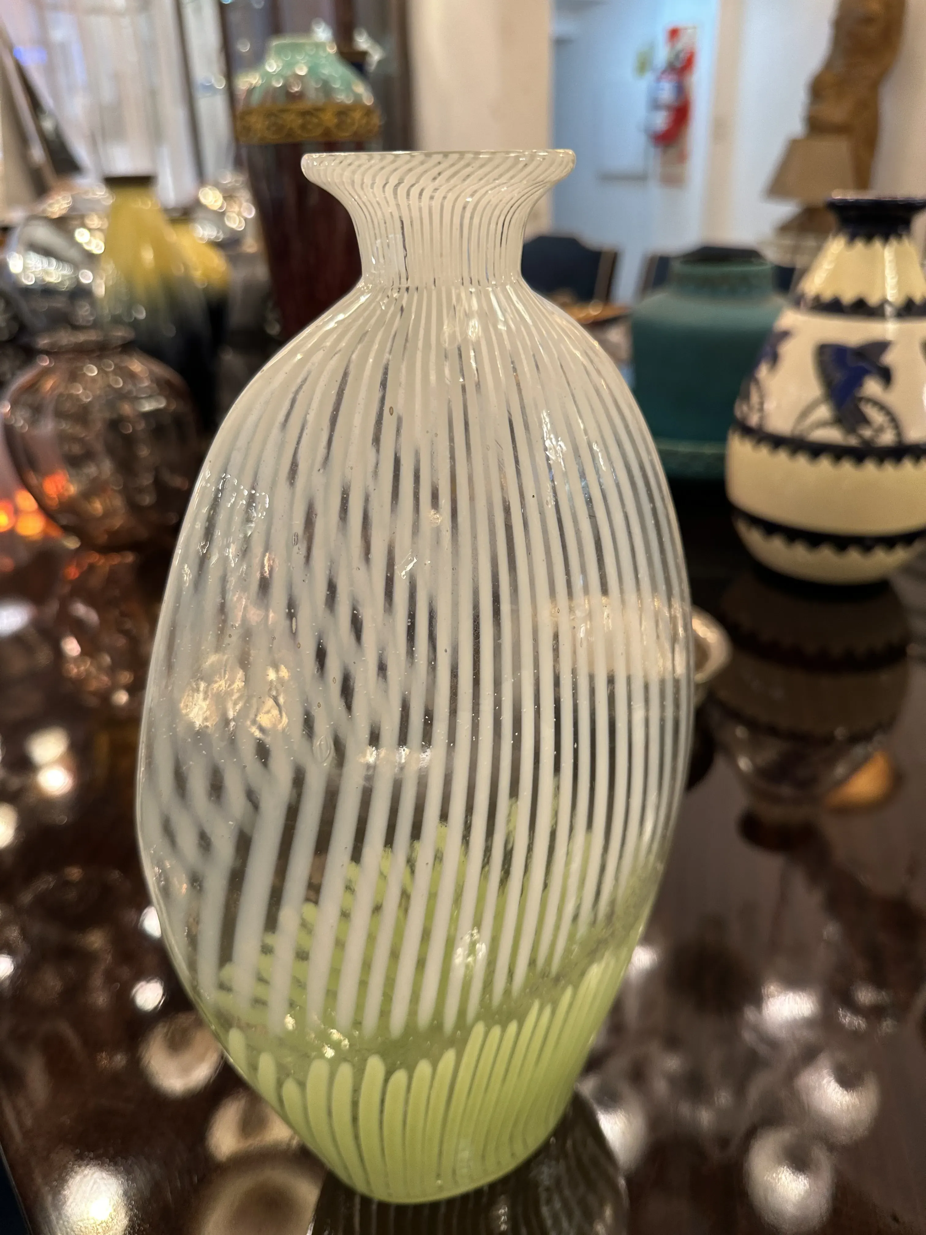 Vase Murano ancien avec un design décoratif et une forme unique, entouré d'autres objets