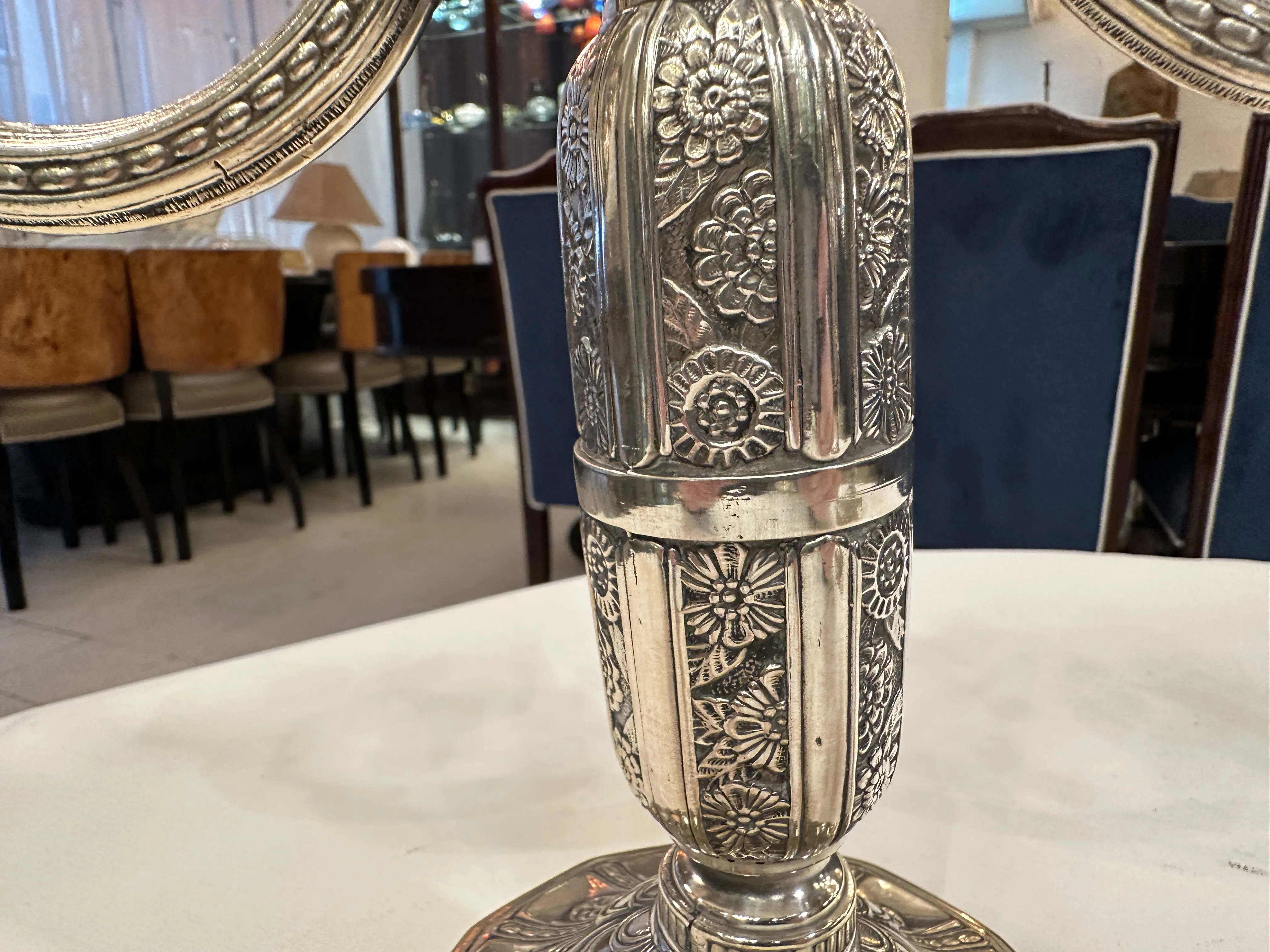 Two antique candlesticks with floral details, placed on a white table, in a classic and elegant setting.