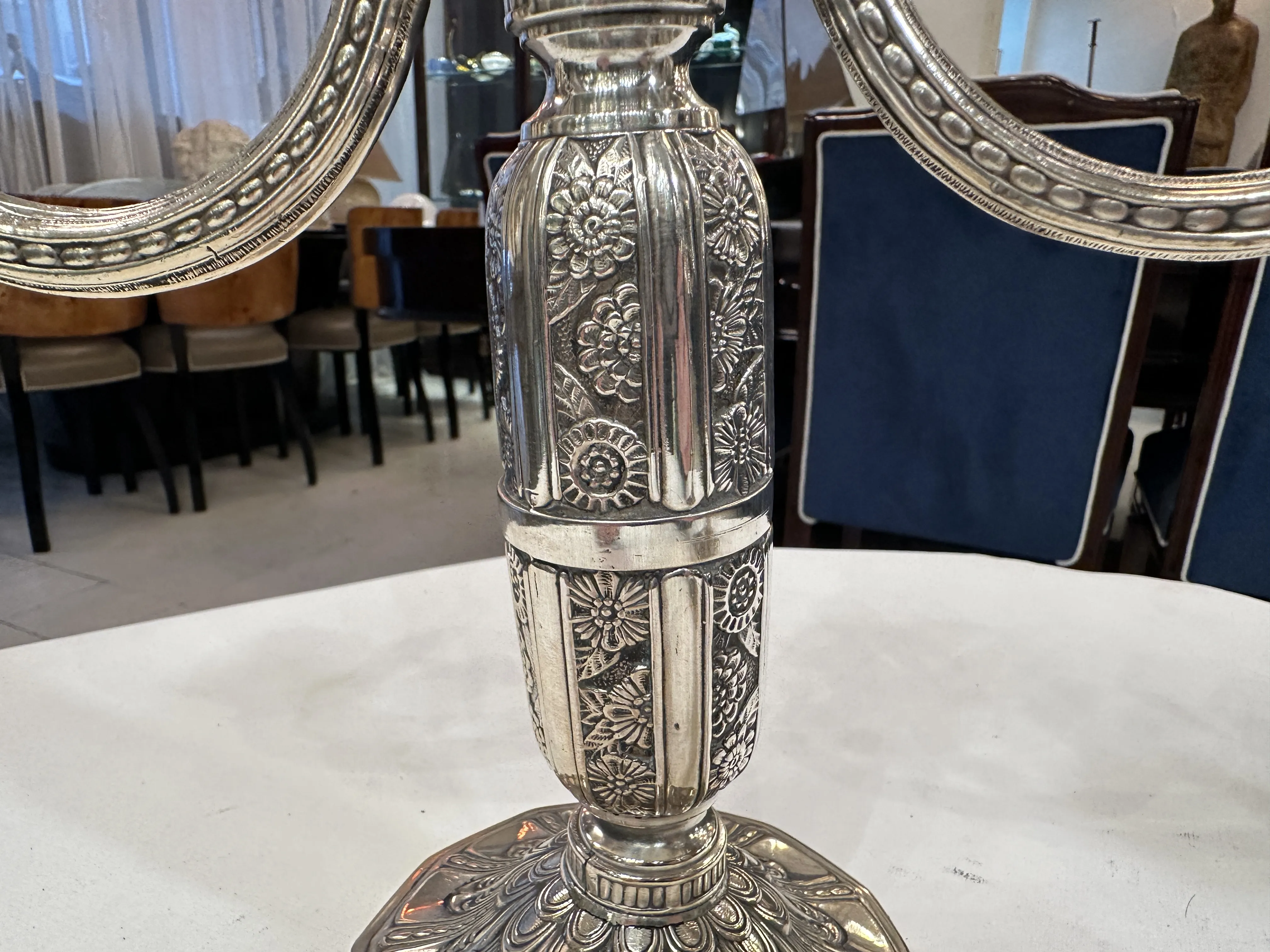 Antique candlesticks in an elegant setting with chairs.