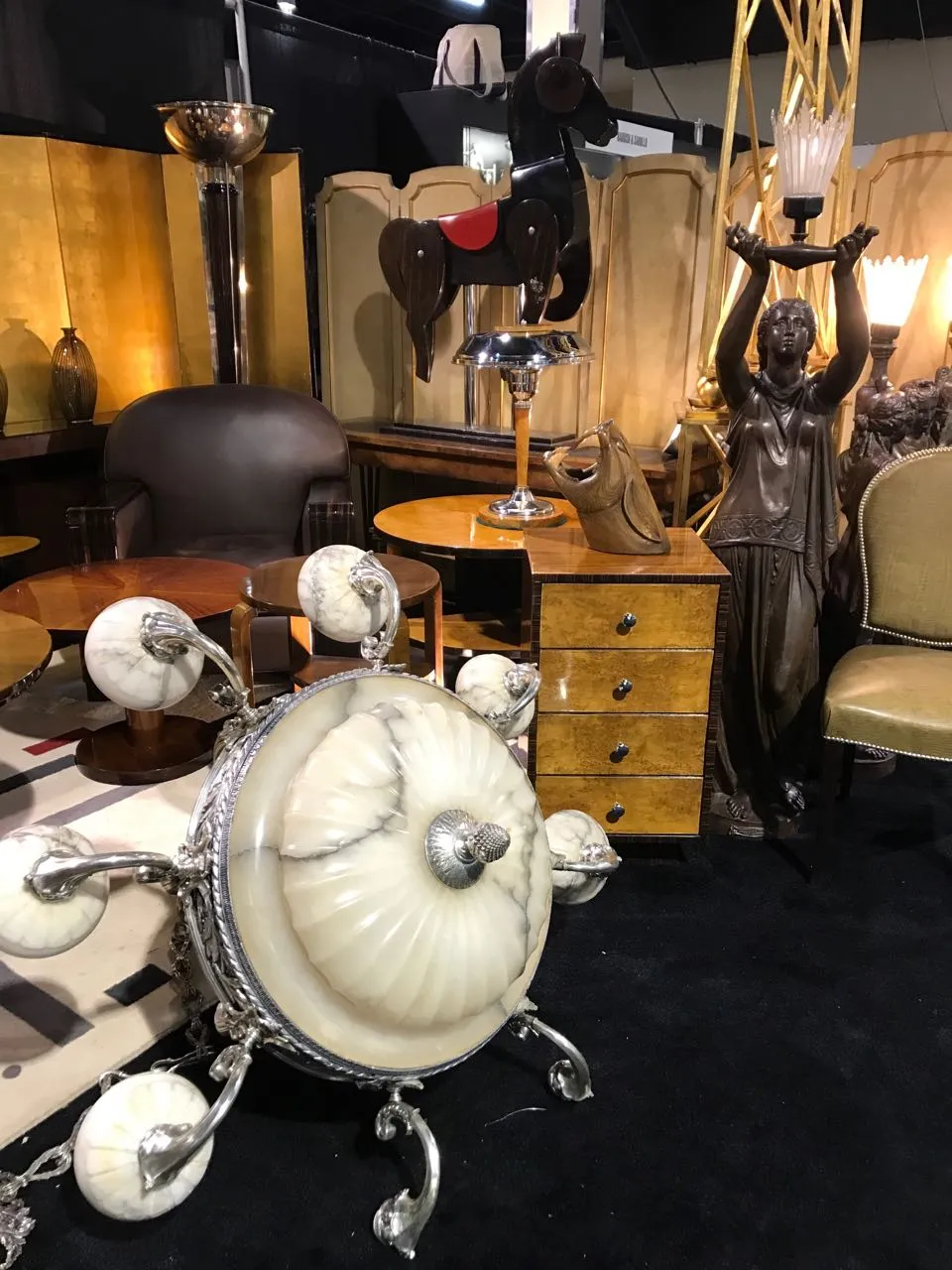 Antigua cómoda clásica con detalles decorativos y patas elegantes en un ambiente de mercado de antigüedades.