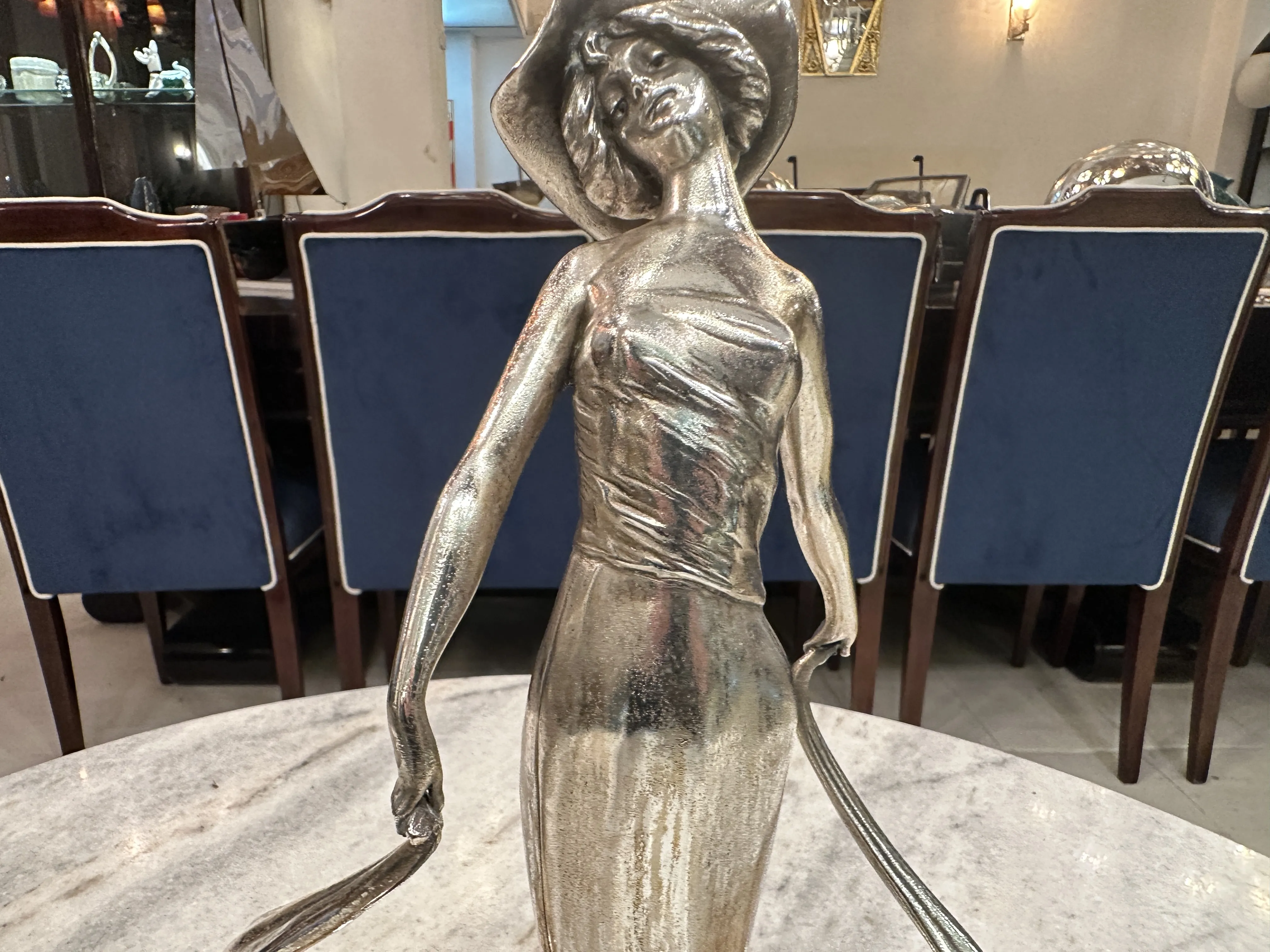 Statue of a woman in a hat in an elegant setting.