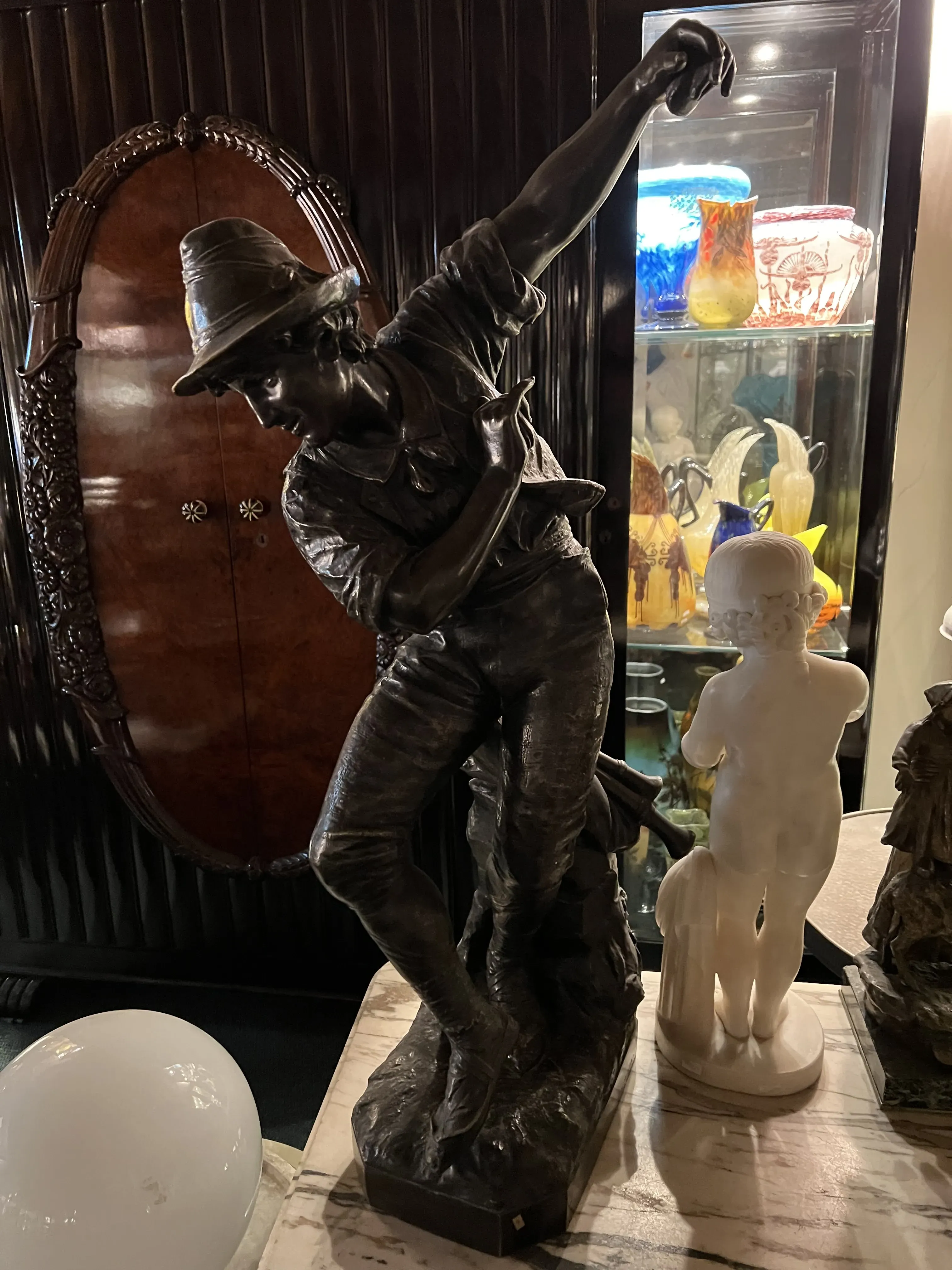 escultura antiga de um homem com chapéu levantando o braço