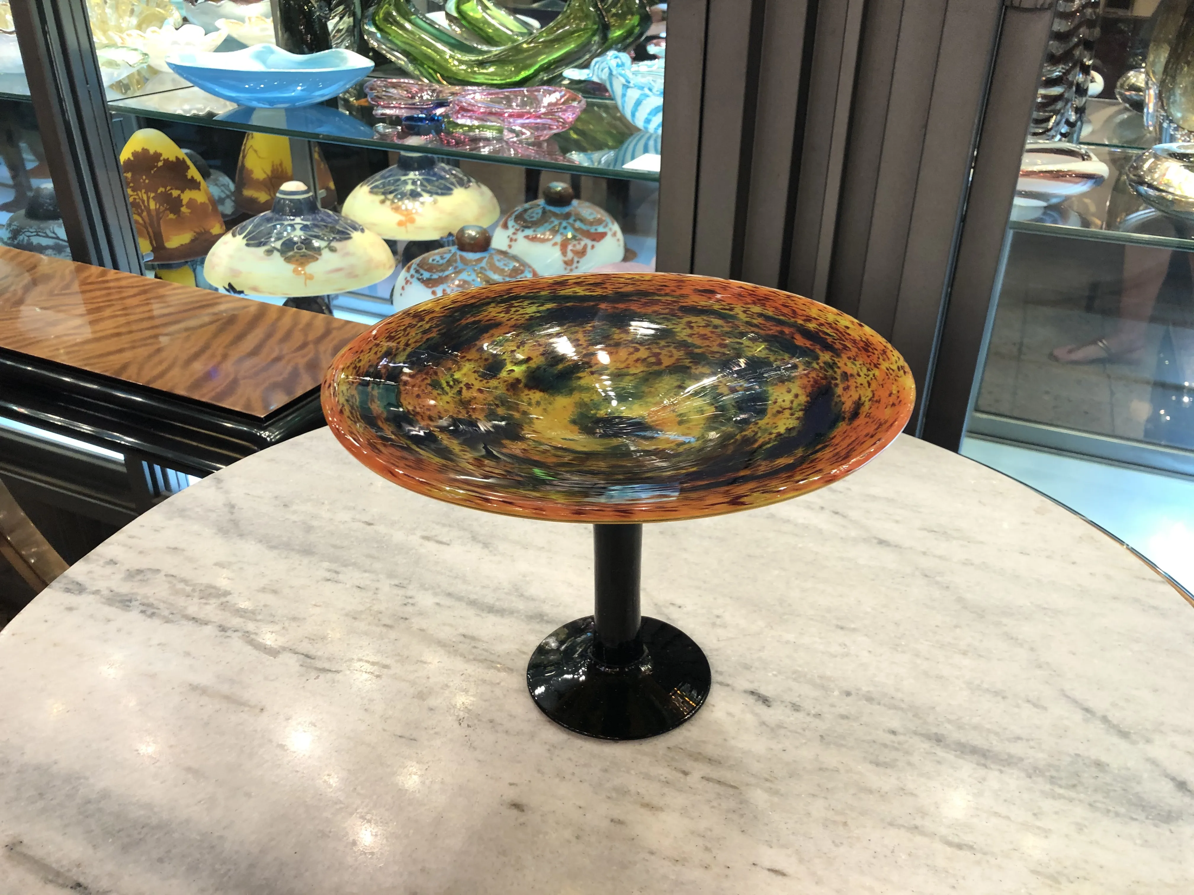 antique glass piece with black base and vibrant colors, displayed background