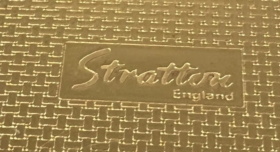 selo antigo com a marca Stratton England em fundo dourado