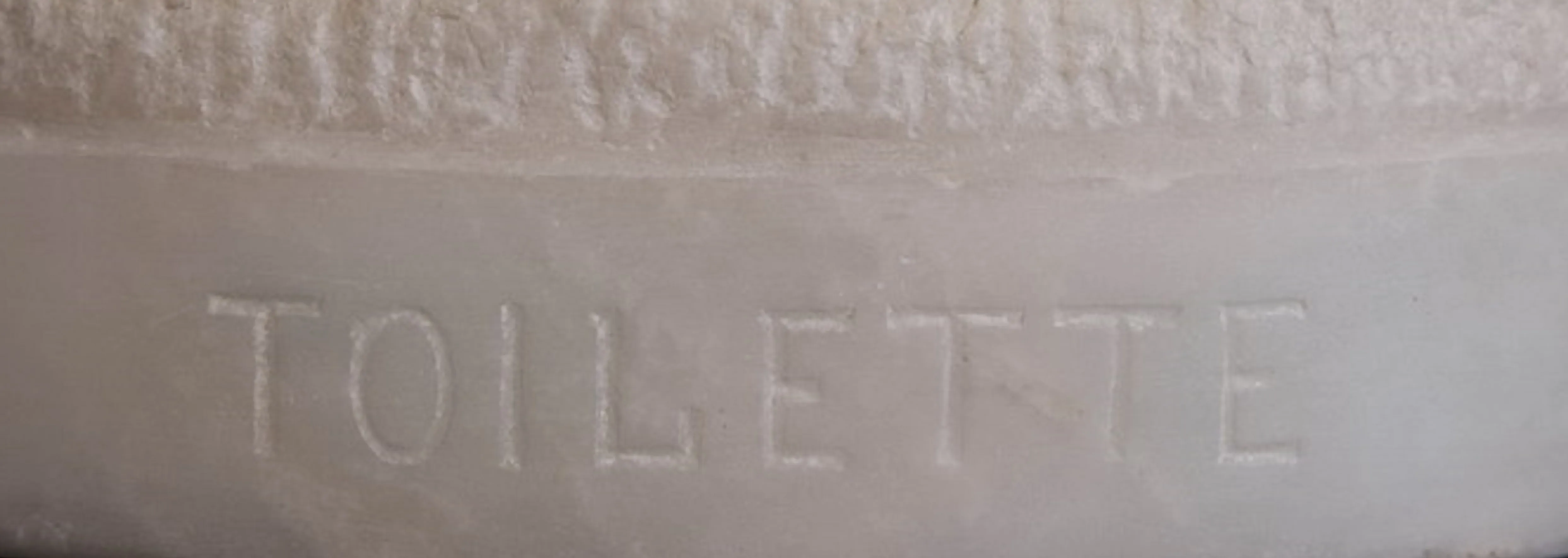 Selo antigo com a palavra 'Toilette' em um design simples.