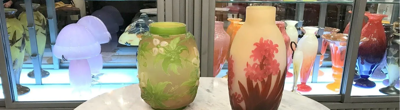 两只装饰有花卉图案的Gallé玻璃, 新艺术风格, 旁边还有其他装饰物品