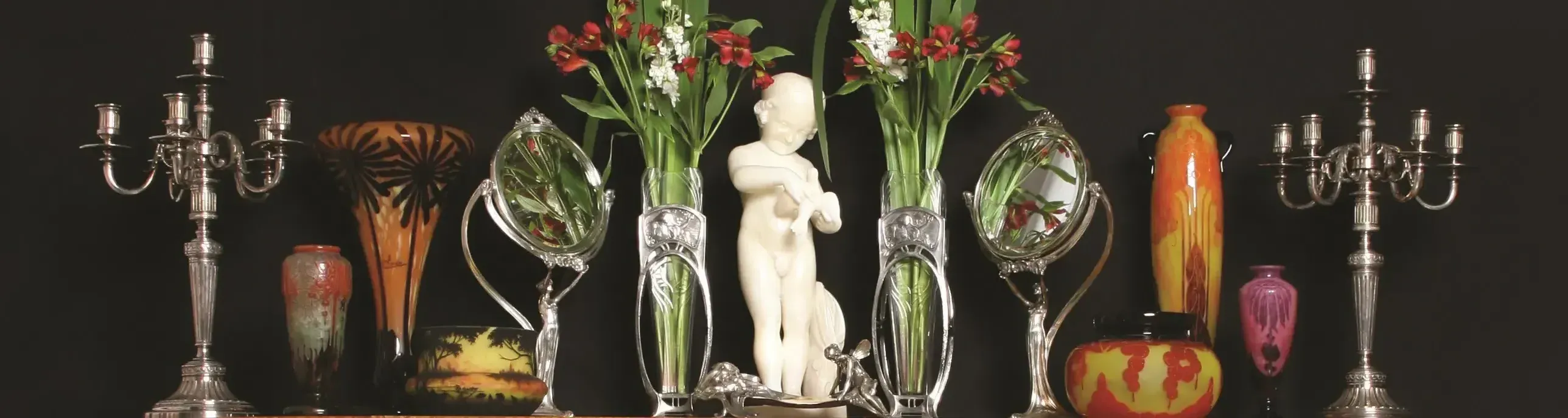 Antike Metallkerzenhalter und Vasen mit Blumen.