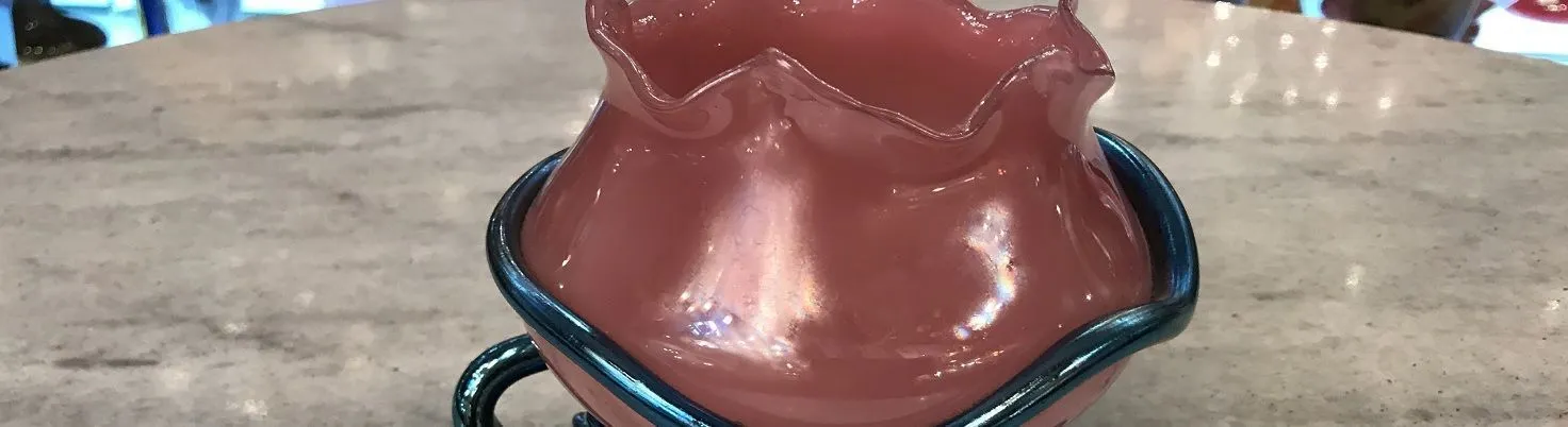 Rosa Glasvase mit blauer Kante und künstlerischem Design.