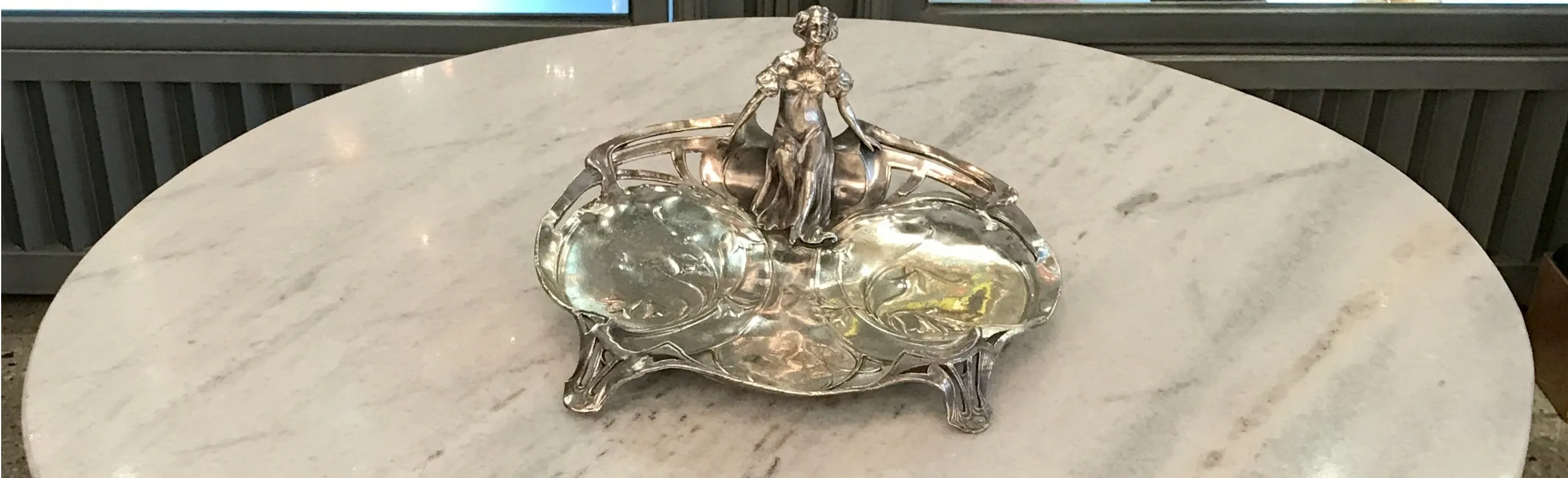 Eleganter antiker Kartenhalter mit künstlerischen Details und einer weiblichen Figur, auf einem Marmorhintergrund.