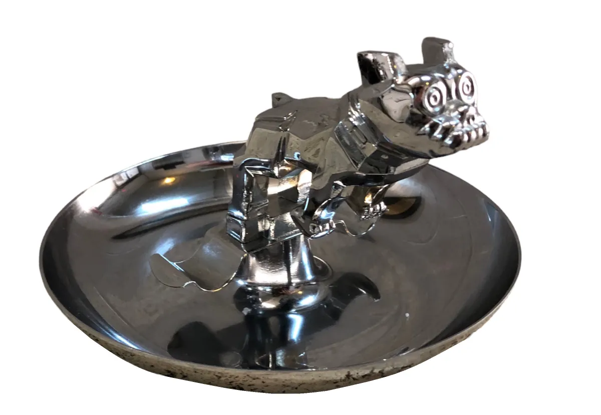Antique ashtray featuring a shiny dog figure and a reflective surface.