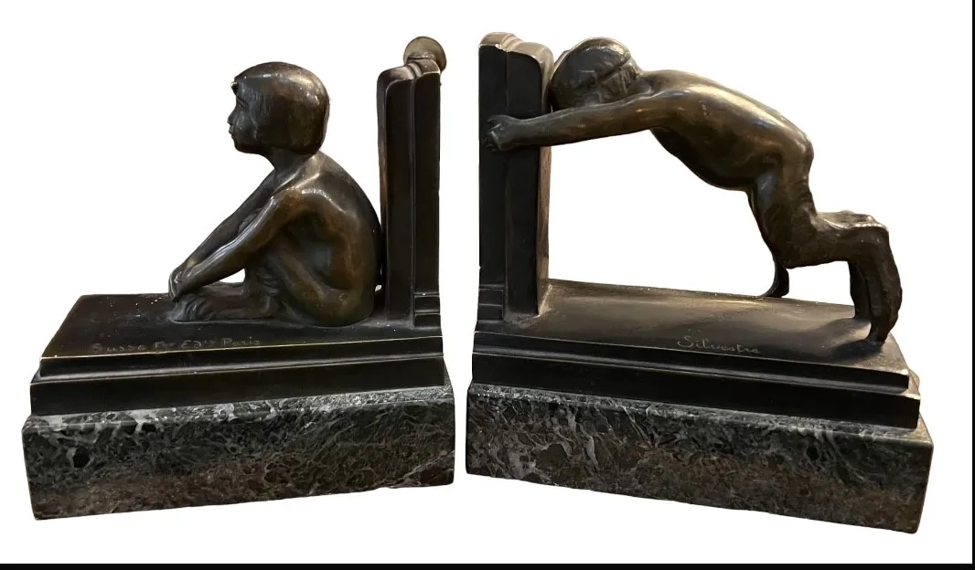 Antique bookends featuring child figures, one seated and one standing.
