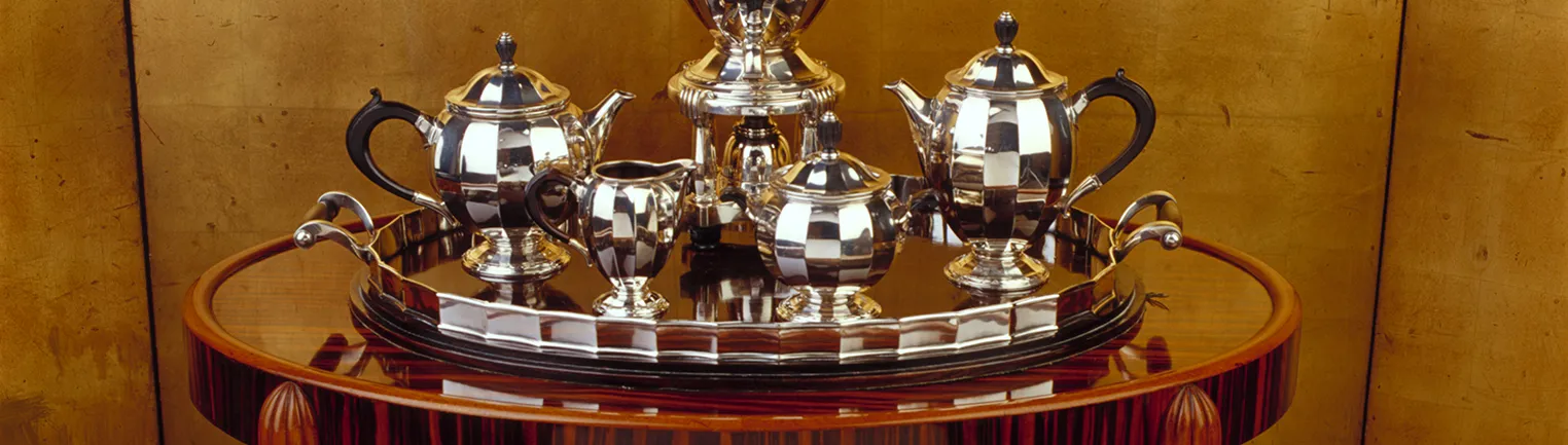 Elegant antique tea and coffee set displayed on shiny tray