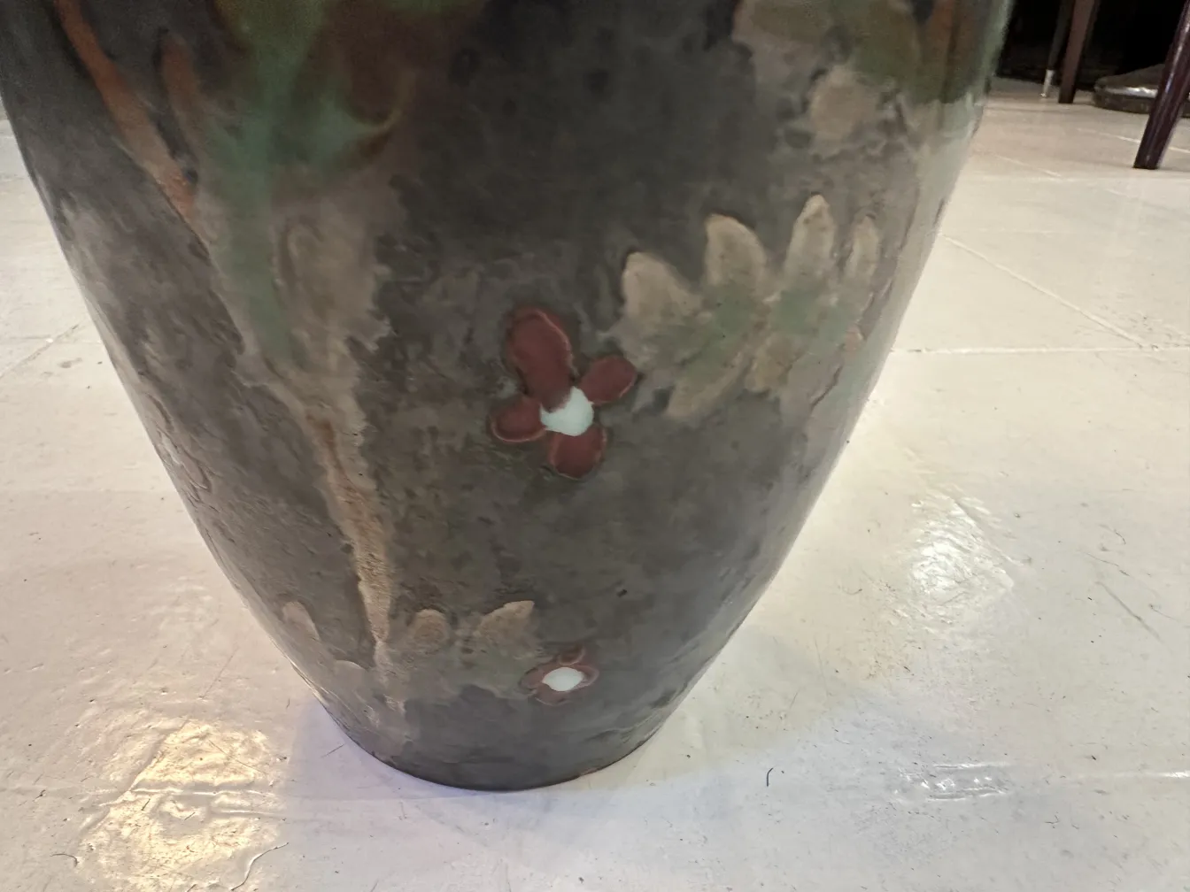 Vaso di ceramica antica decorato con fiori colorati in un ambiente semplice.