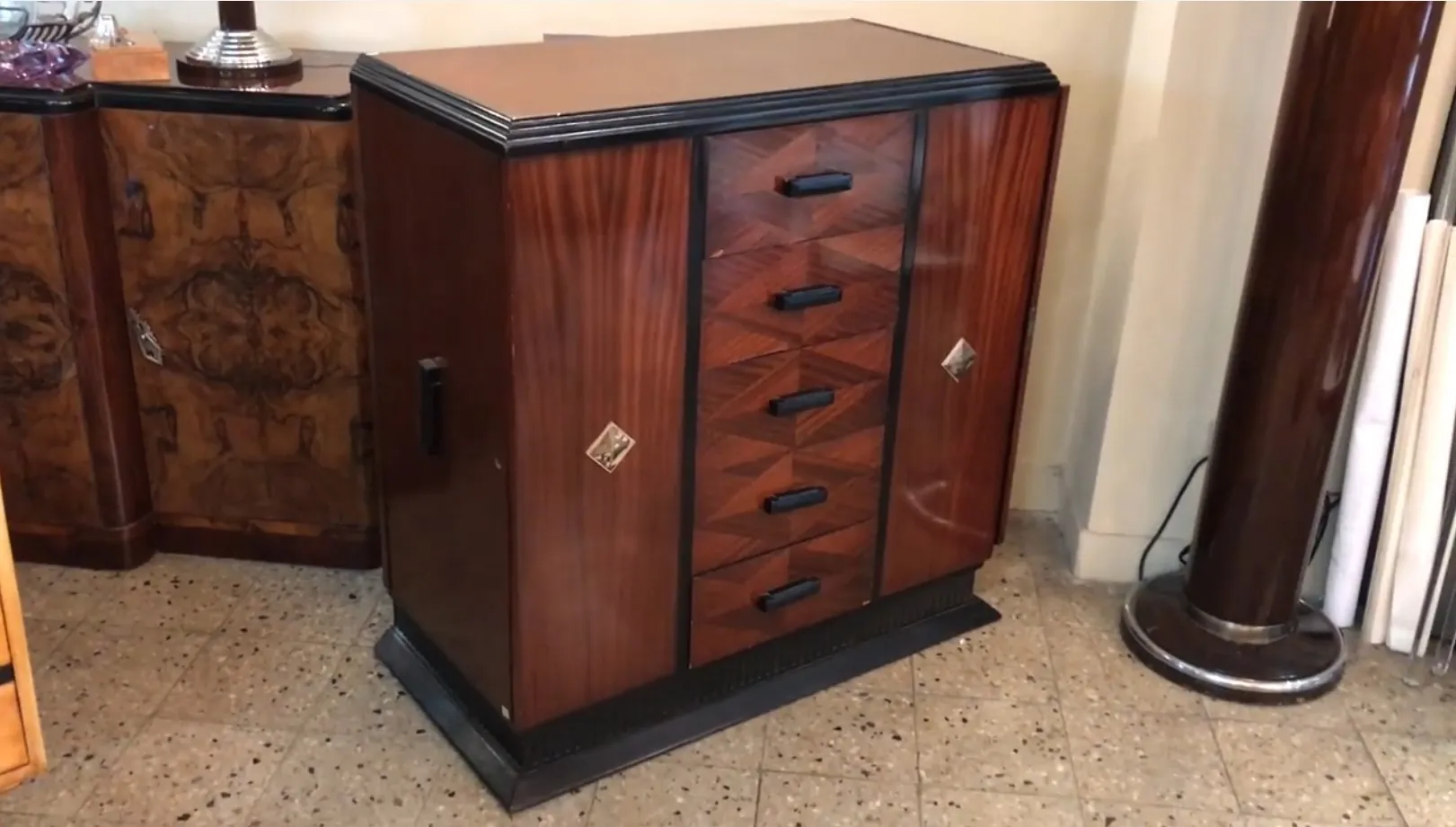 Cassettiera antica con finitura in legno e dieci cassetti neri.