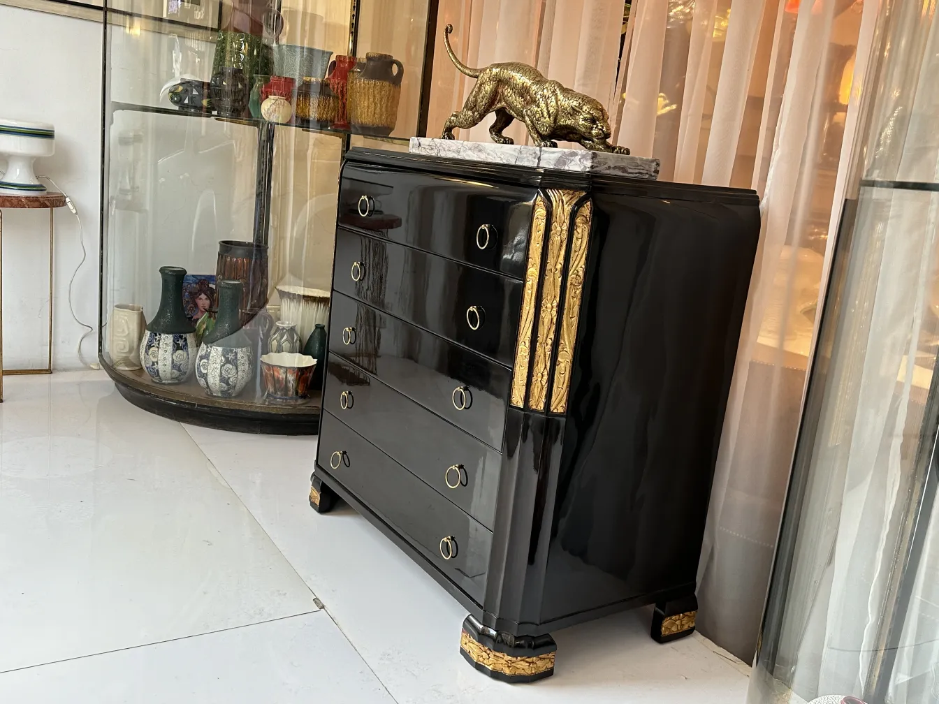 Gaveteira antiga preta com detalhes dourados em um ambiente elegante.