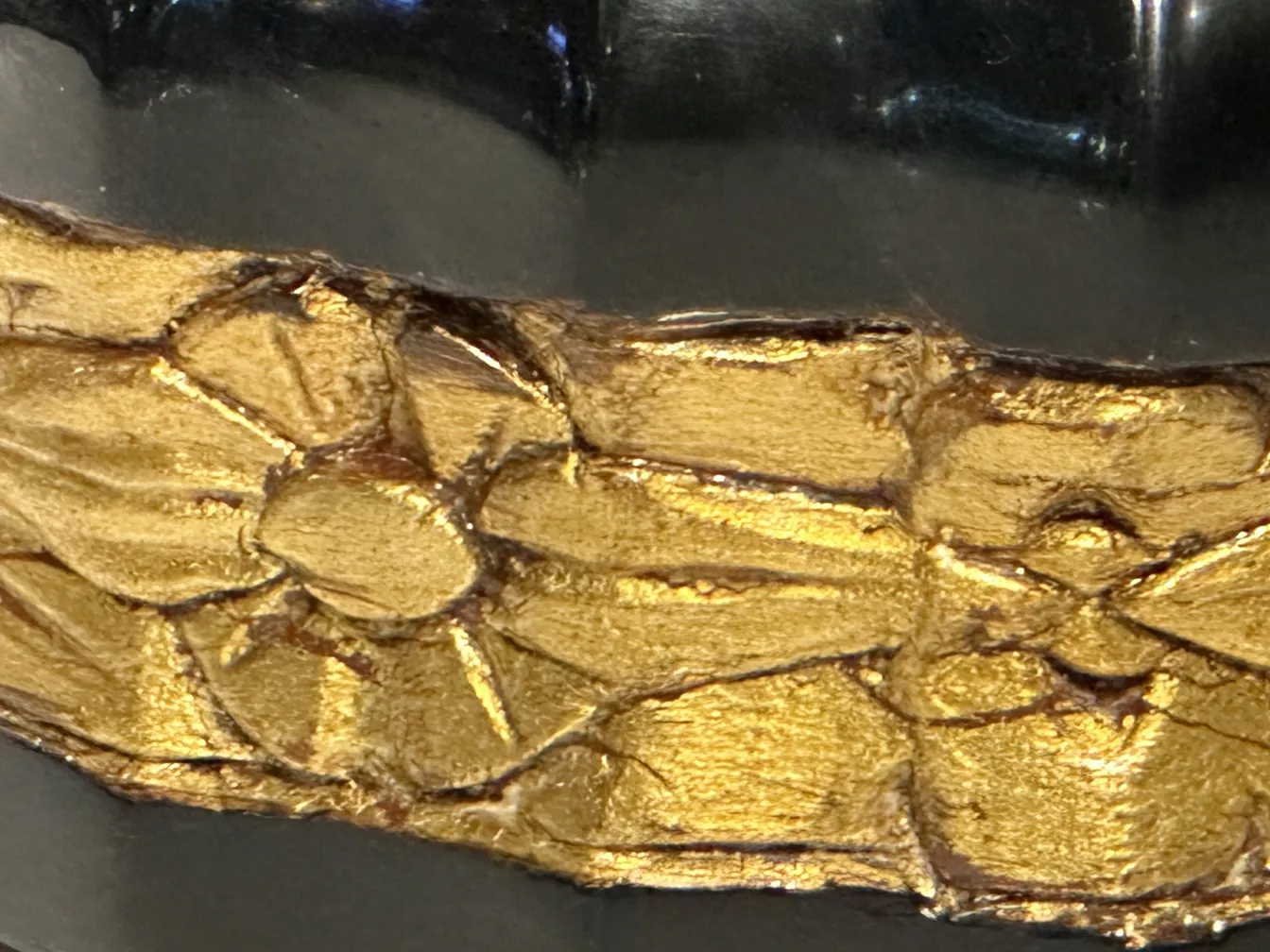 Detalles dorados en una cómoda antigua, destacada contra un fondo oscuro.