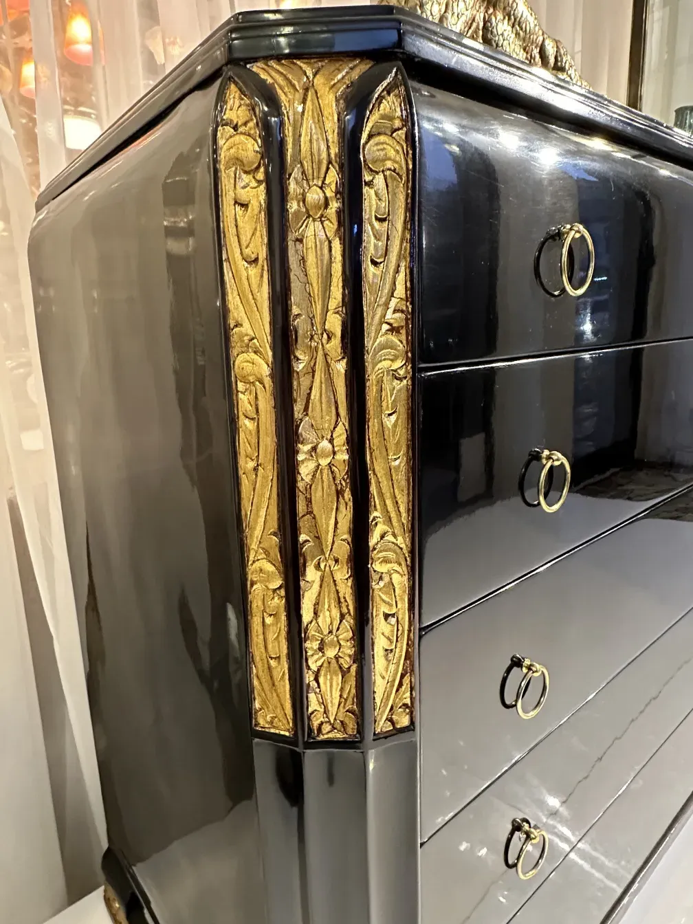 Commode ancienne avec détails dorés et anneaux en métal.