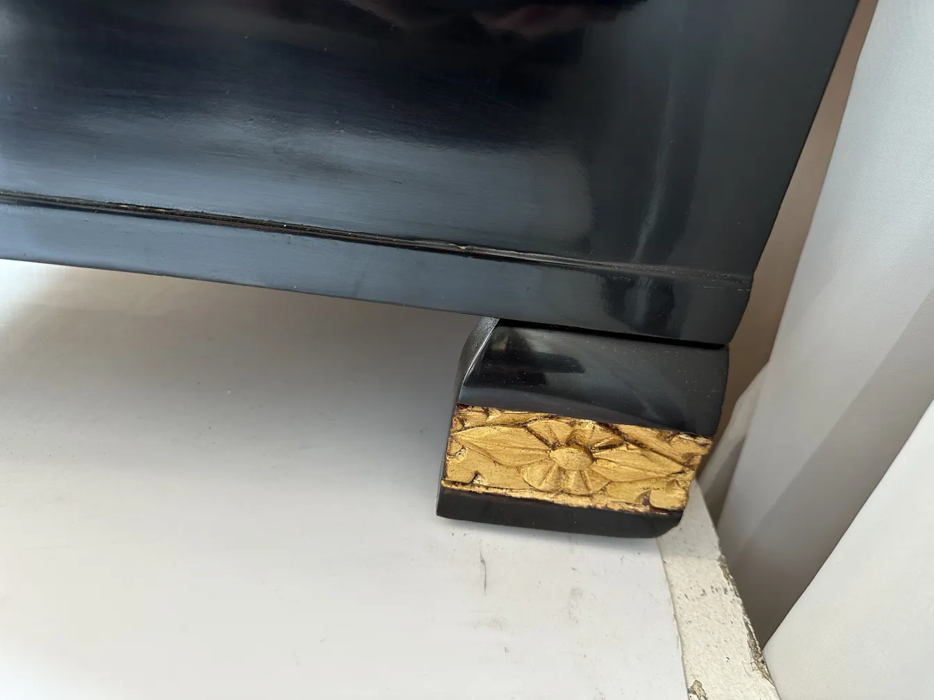 Gaveteira antiga com base de flor dourada em relevo.