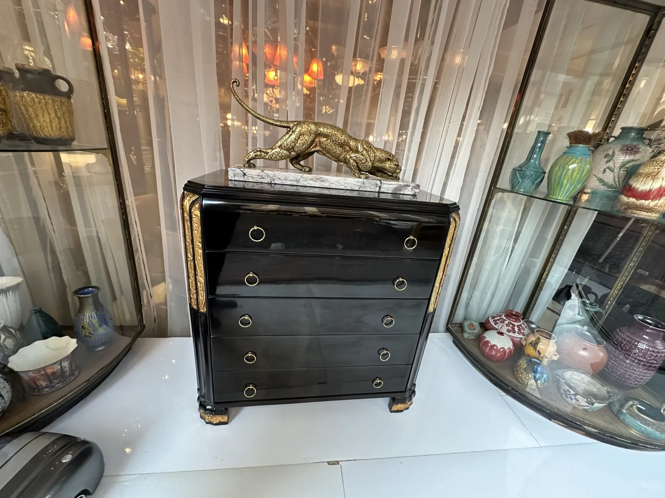 Commode ancienne brillante avec des détails dorés et un lion décoratif.