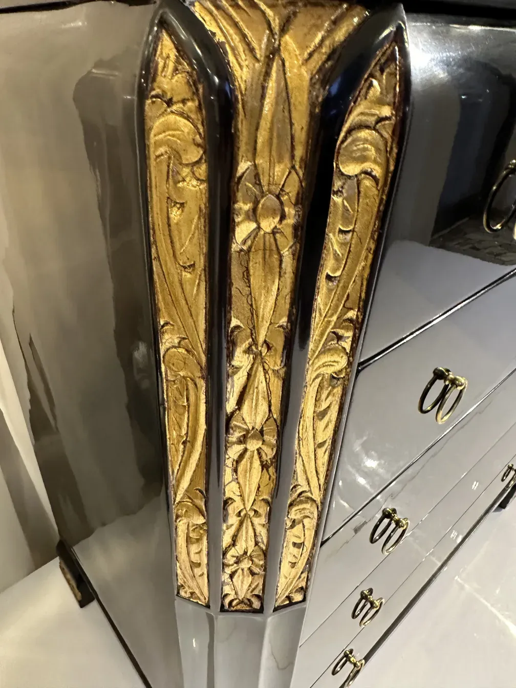 Gaveteira antiga com decorações em relevo douradas, elegante e estilizada.