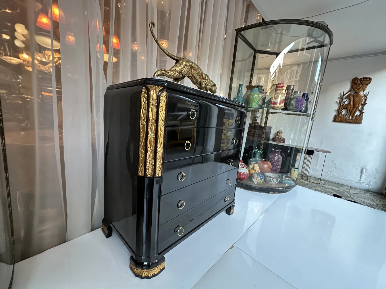 Gaveteira antiga com acabamento elegante em preto e dourado e detalhes decorativos.