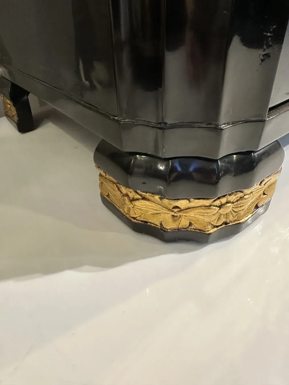 Comoda antigua con base negra y detalles dorados