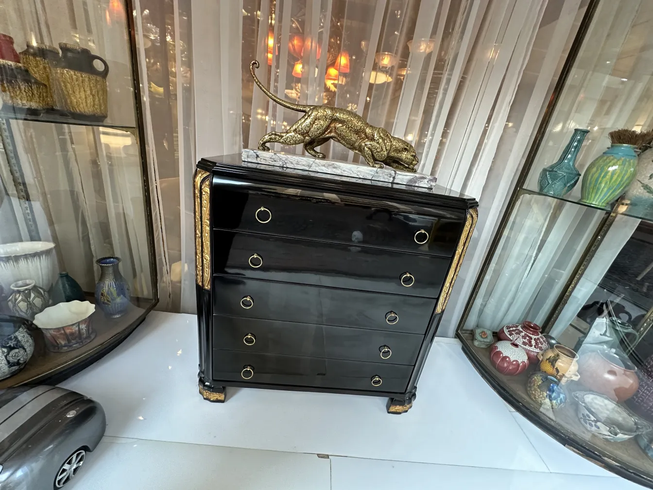 Antique black cabinet with golden details and a decorative lion.