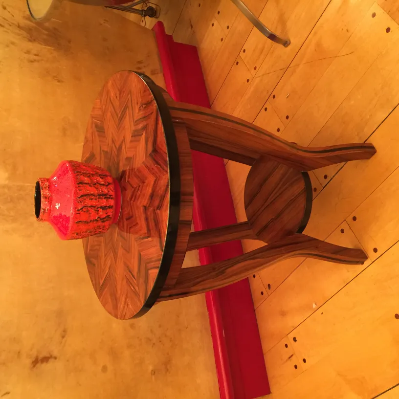 Jarrón de cerámica antigua en mesa con patrones de madera.