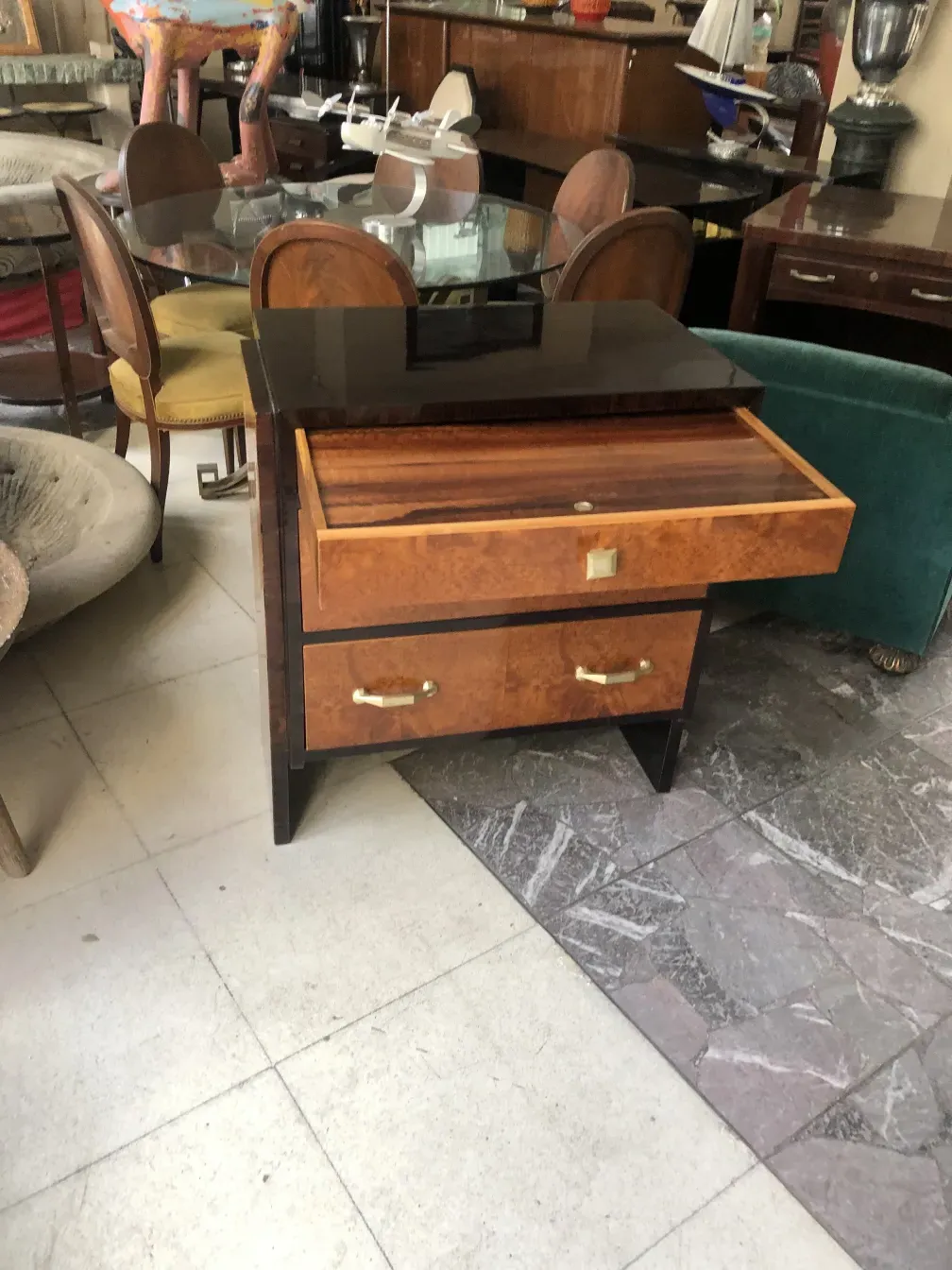 Comoda antigua de madera, con dos cajones y un acabado brillante, en un entorno de muebles vintage.
