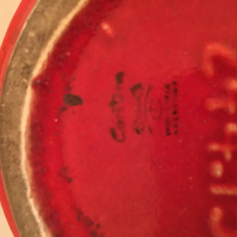 Détail d'une ancienne céramique rouge avec des marques visibles.