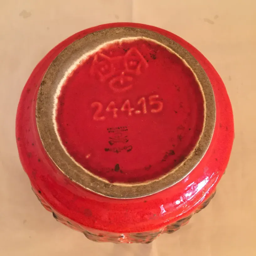 Vue de la base d'une céramique ancienne avec une couleur rouge vibrante et détails visibles