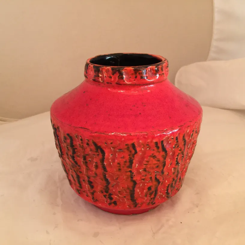 Vaso in ceramica antica, colore rosso brillante con texture.