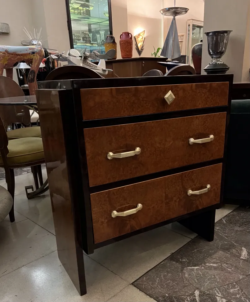 Cómoda antigua de madera con dos cajones y manijas doradas.