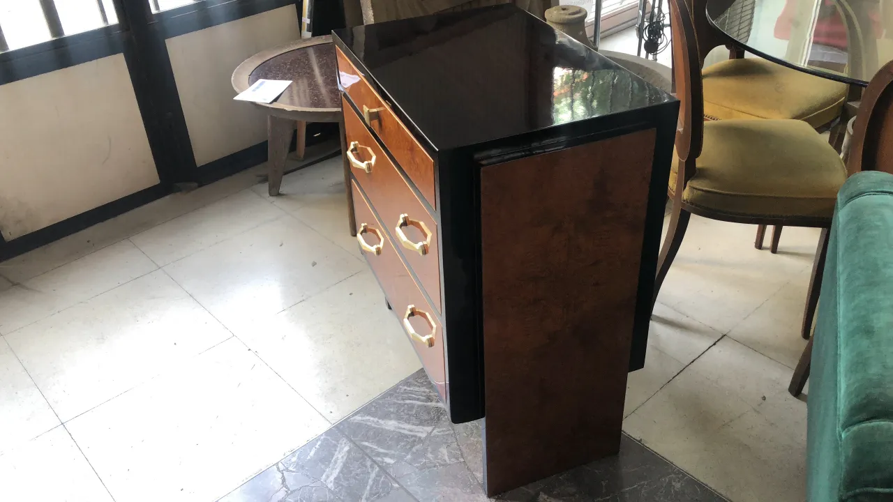Commode ancienne en bois avec trois tiroirs et des pieds, dans un environnement chaleureux.