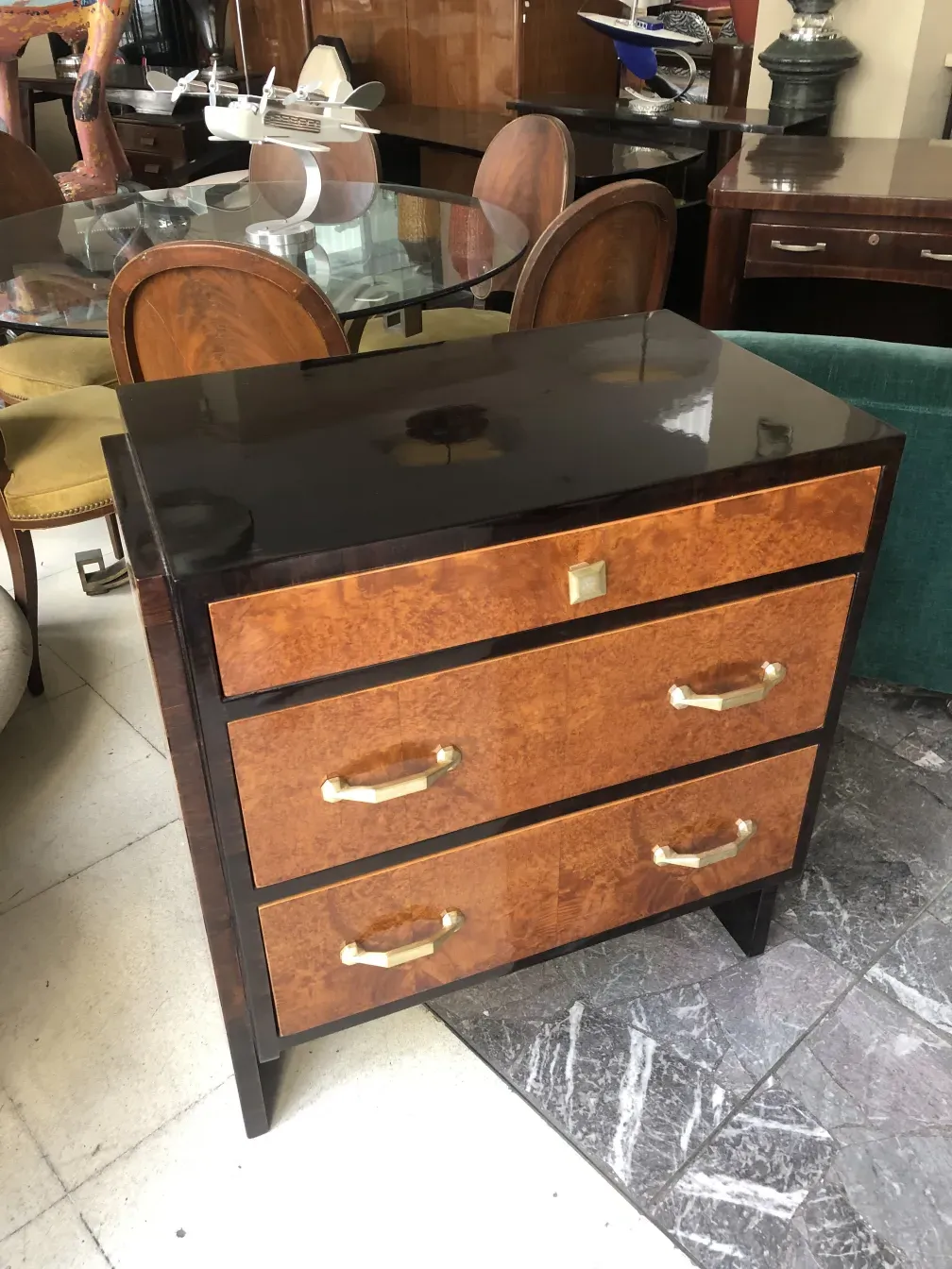 Commode ancienne avec une finition brillante et des poignées dorées.