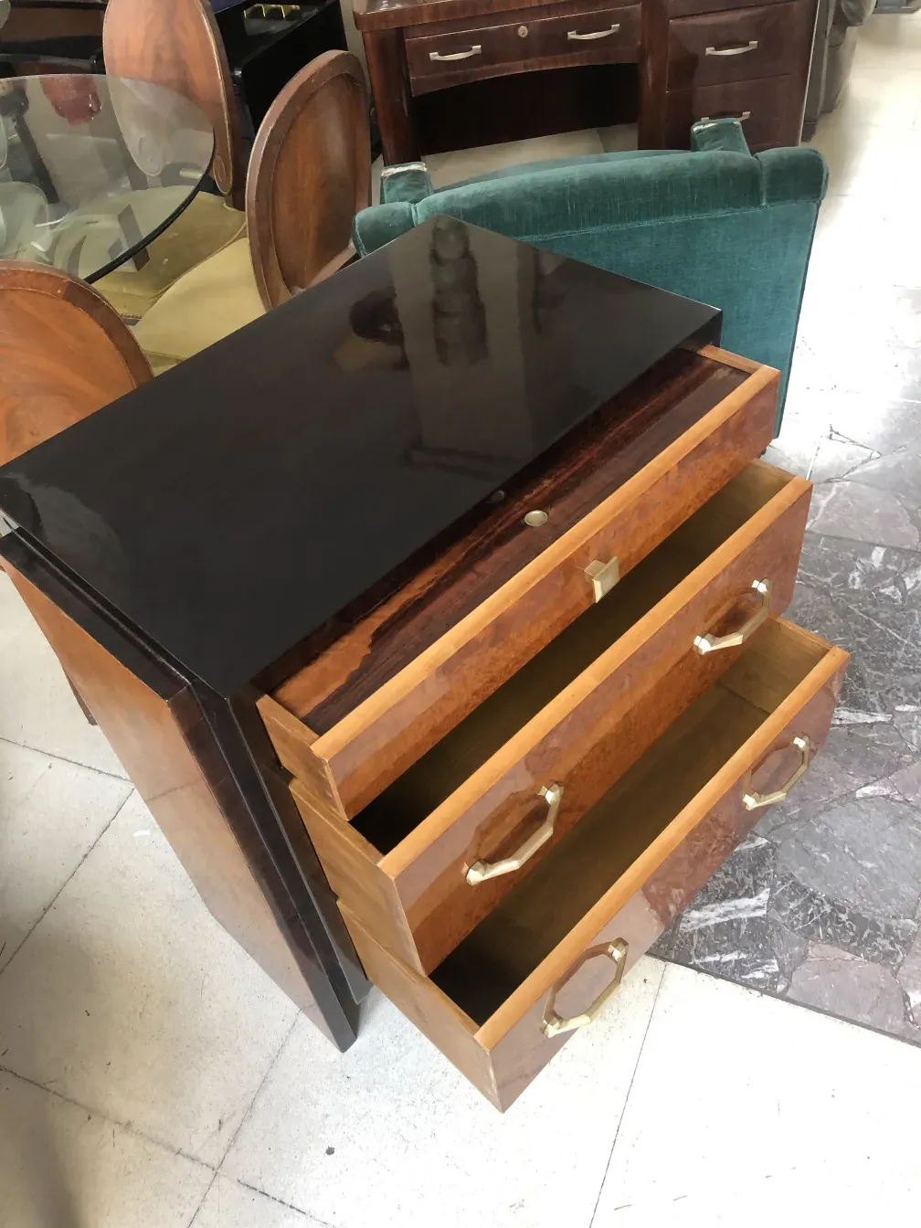 خزانة قديمة من الخشب تحتوي على ثلاثة أدراج ومقابض ذهبية في بيئة مريحة.