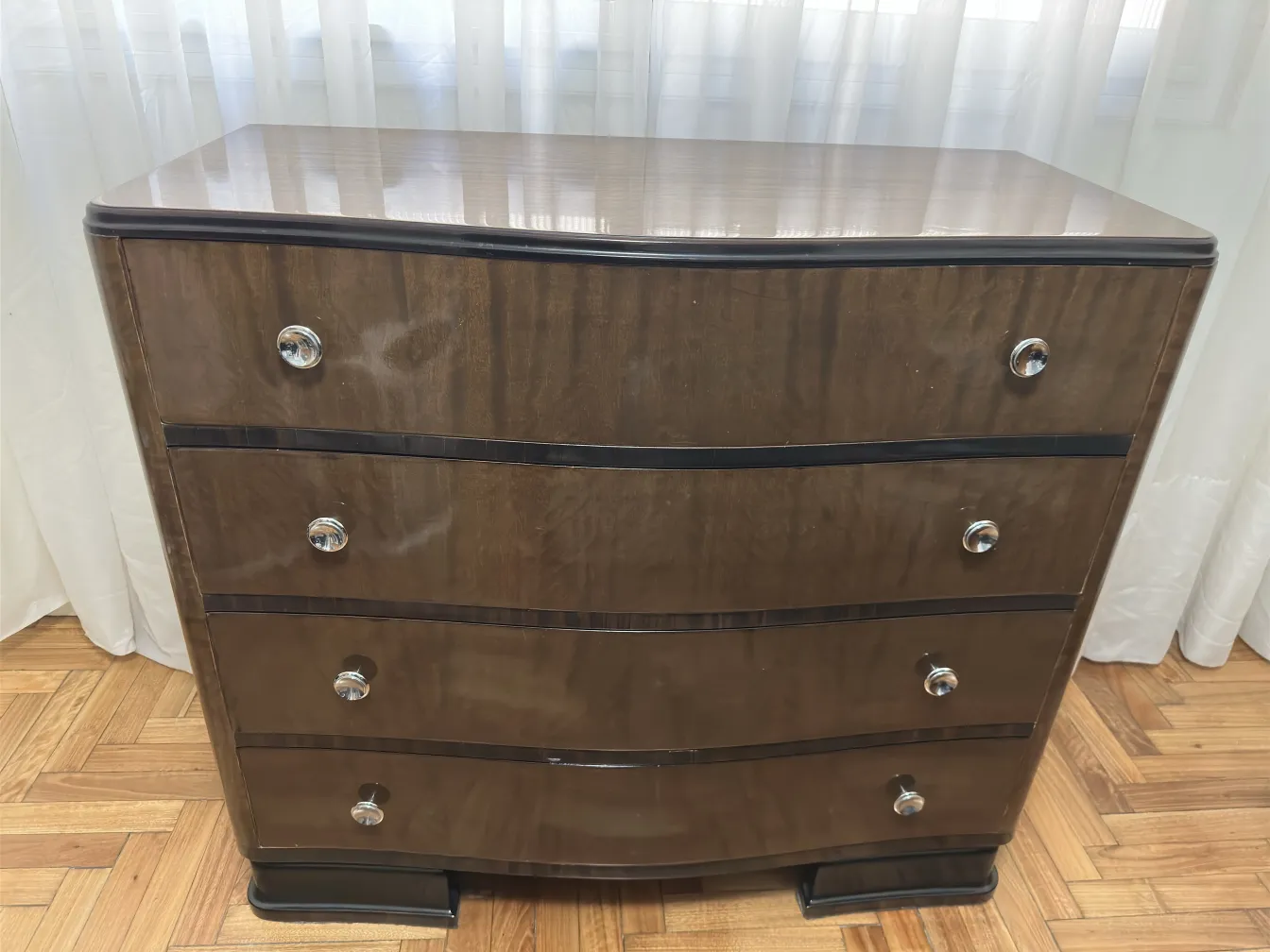 Commode ancienne à quatre tiroirs dans un cadre lumineux.