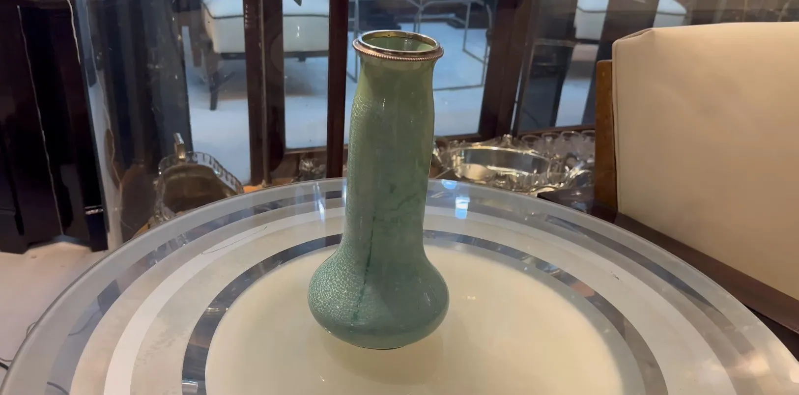 Antique green ceramic vase on a table, blurred background.