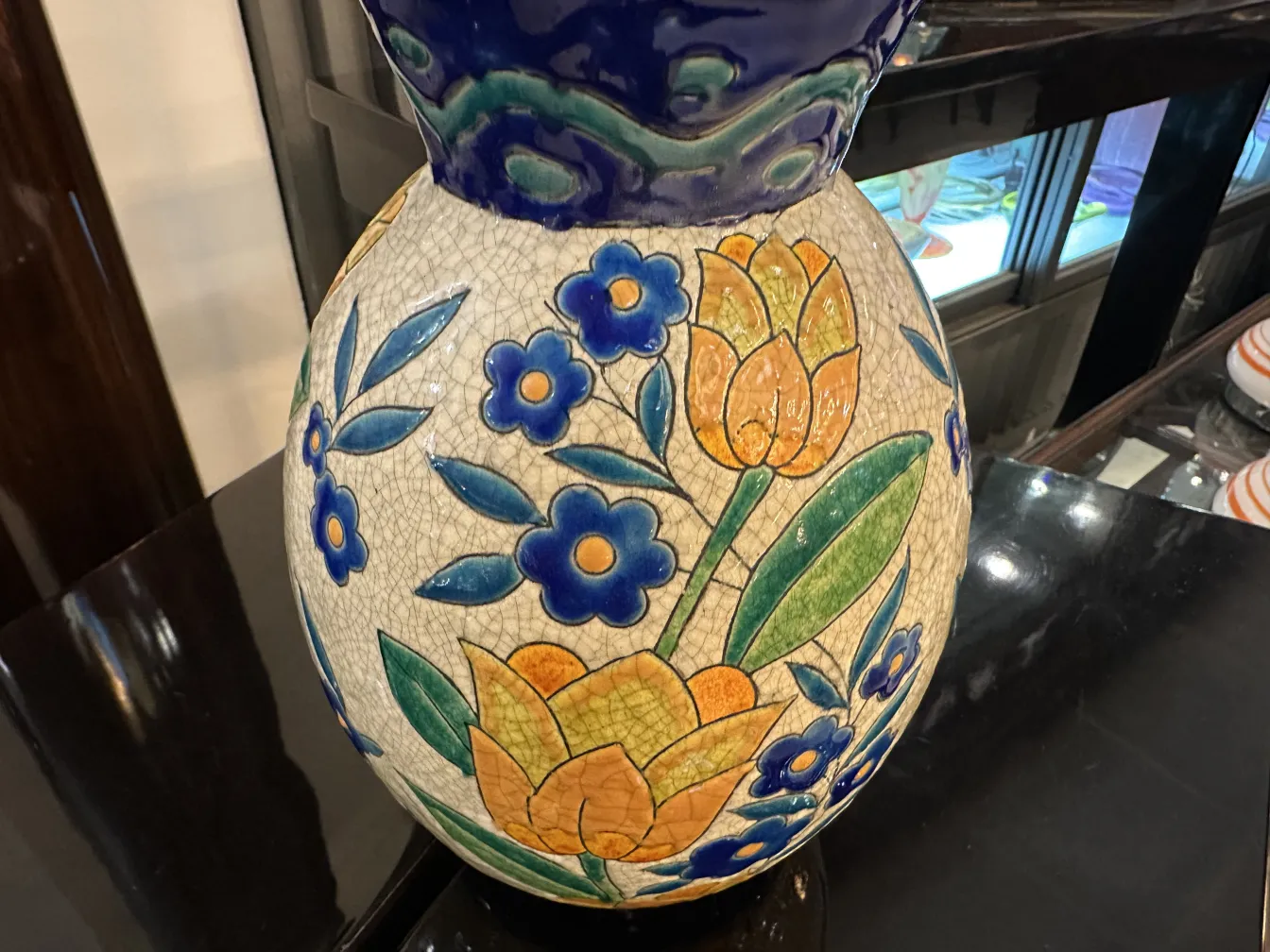 Jarrón de cerámica antigua con flores amarillas y azules sobre fondo claro