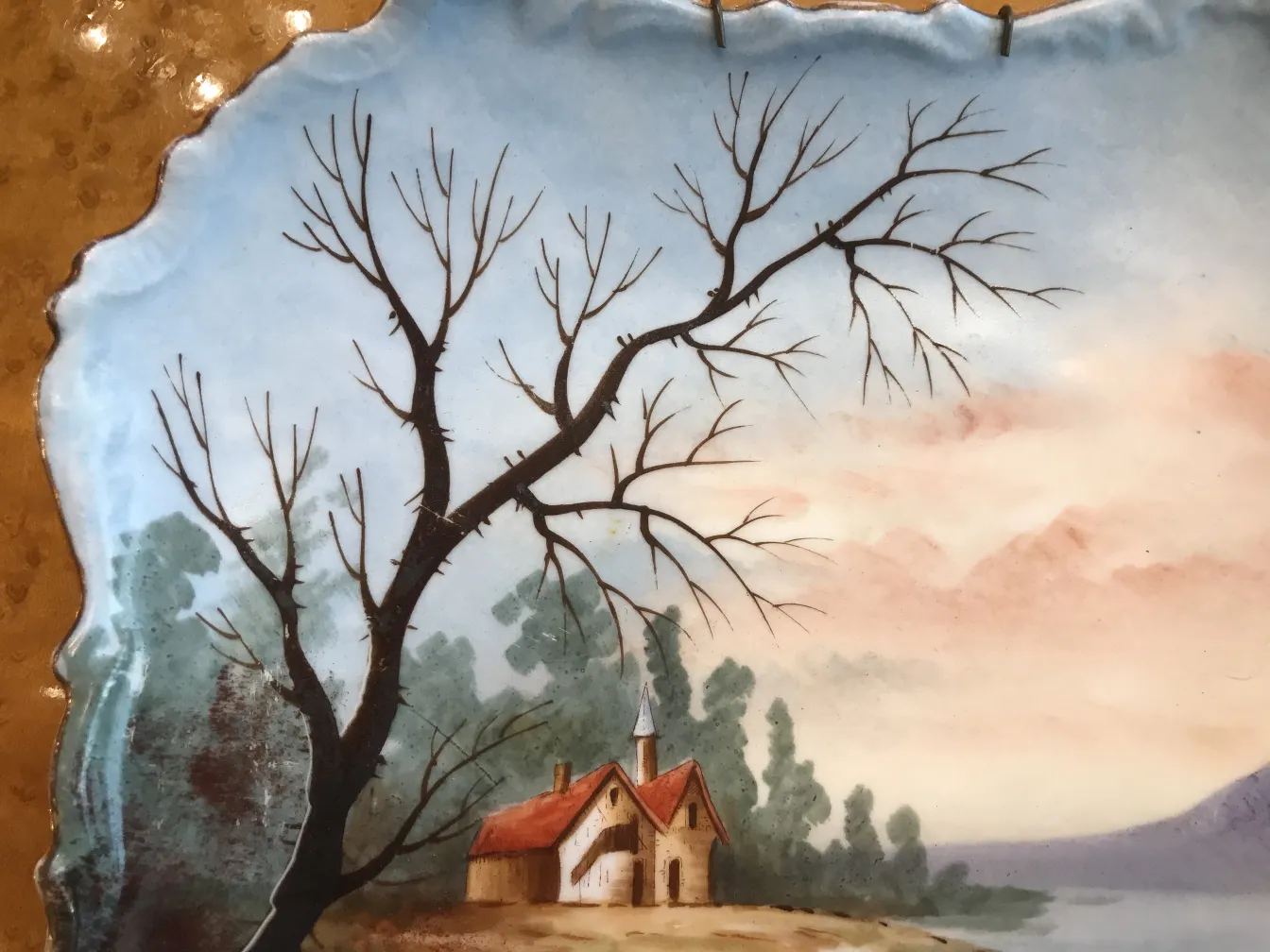Antique ceramic plate featuring a landscape with trees and a house.